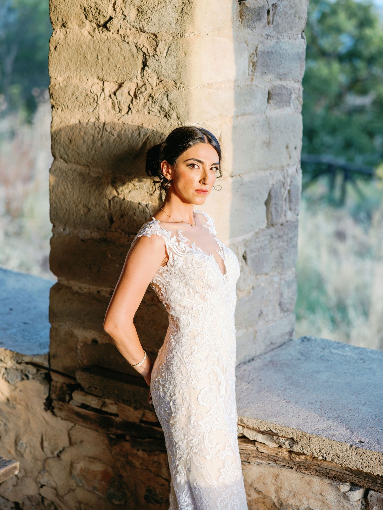 Elegant bridal portraits taken in a rustic stone colonnade with natural lighting.