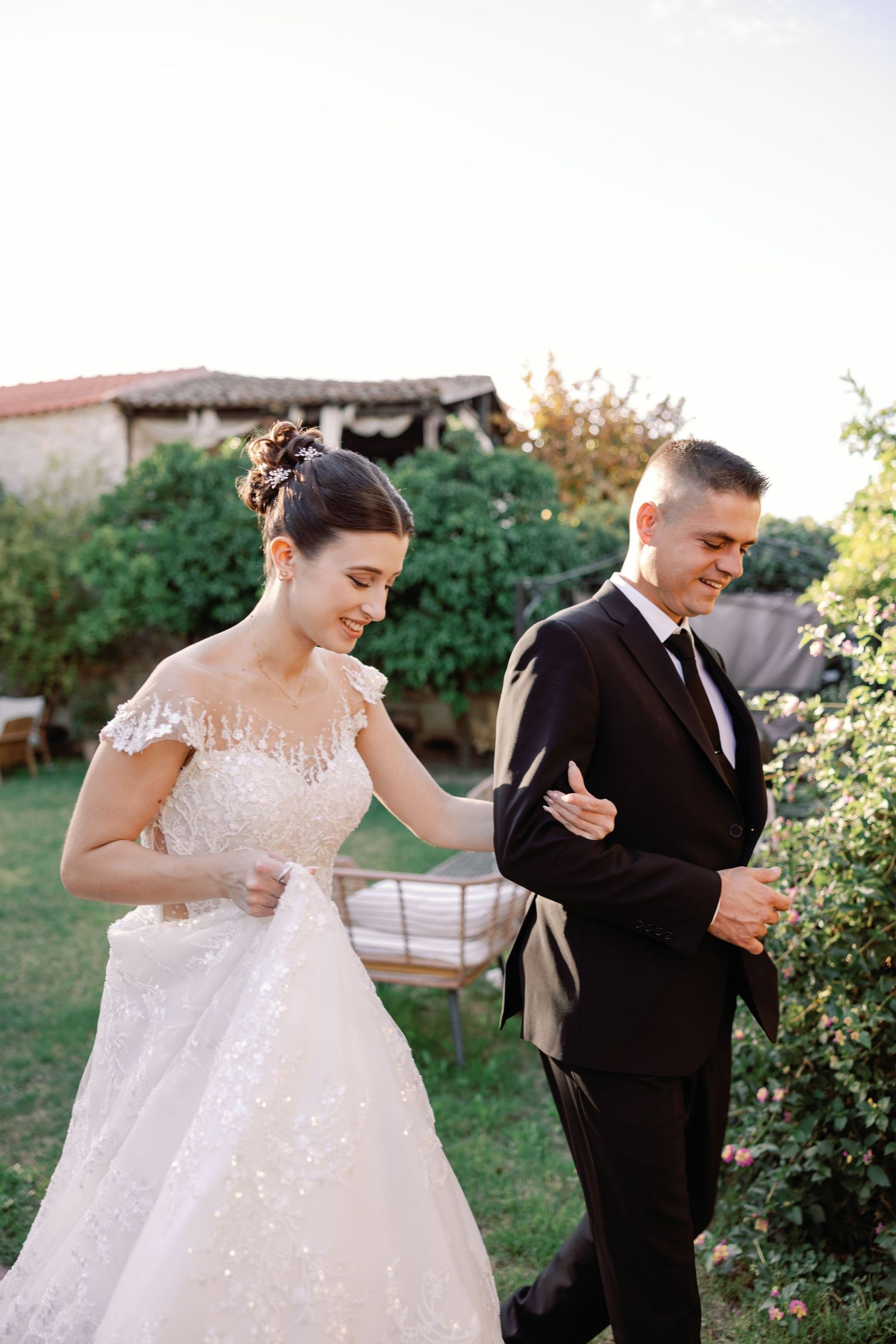Newlyweds share intimate moments in garden setting during sunset.