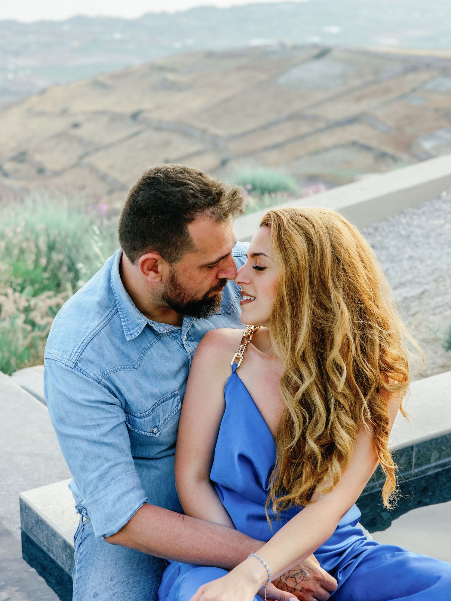 Romantic couple sharing intimate moment on Mediterranean terrace with mountain views.