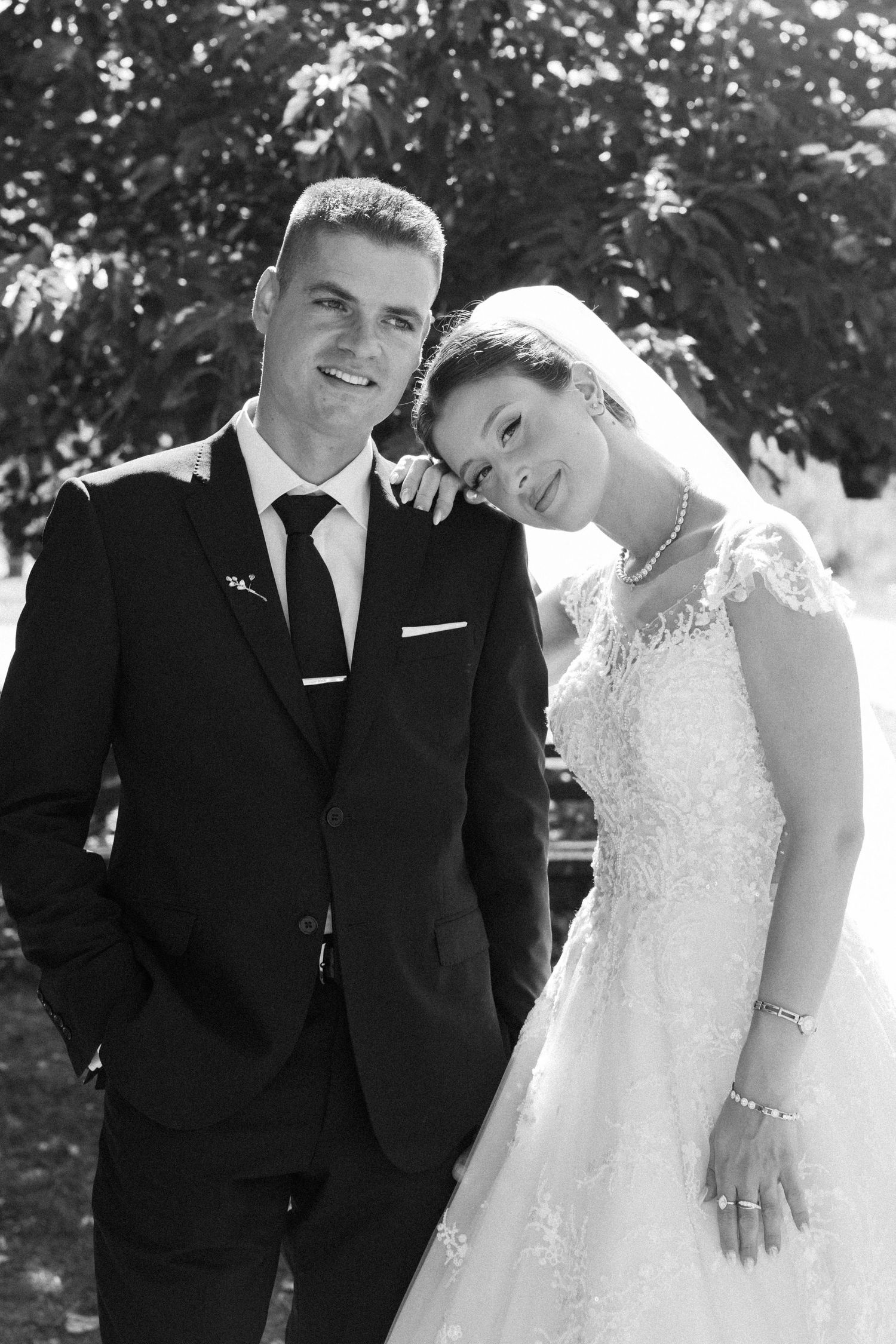 Black and white wedding portrait showing couple in formal attire outdoors.
