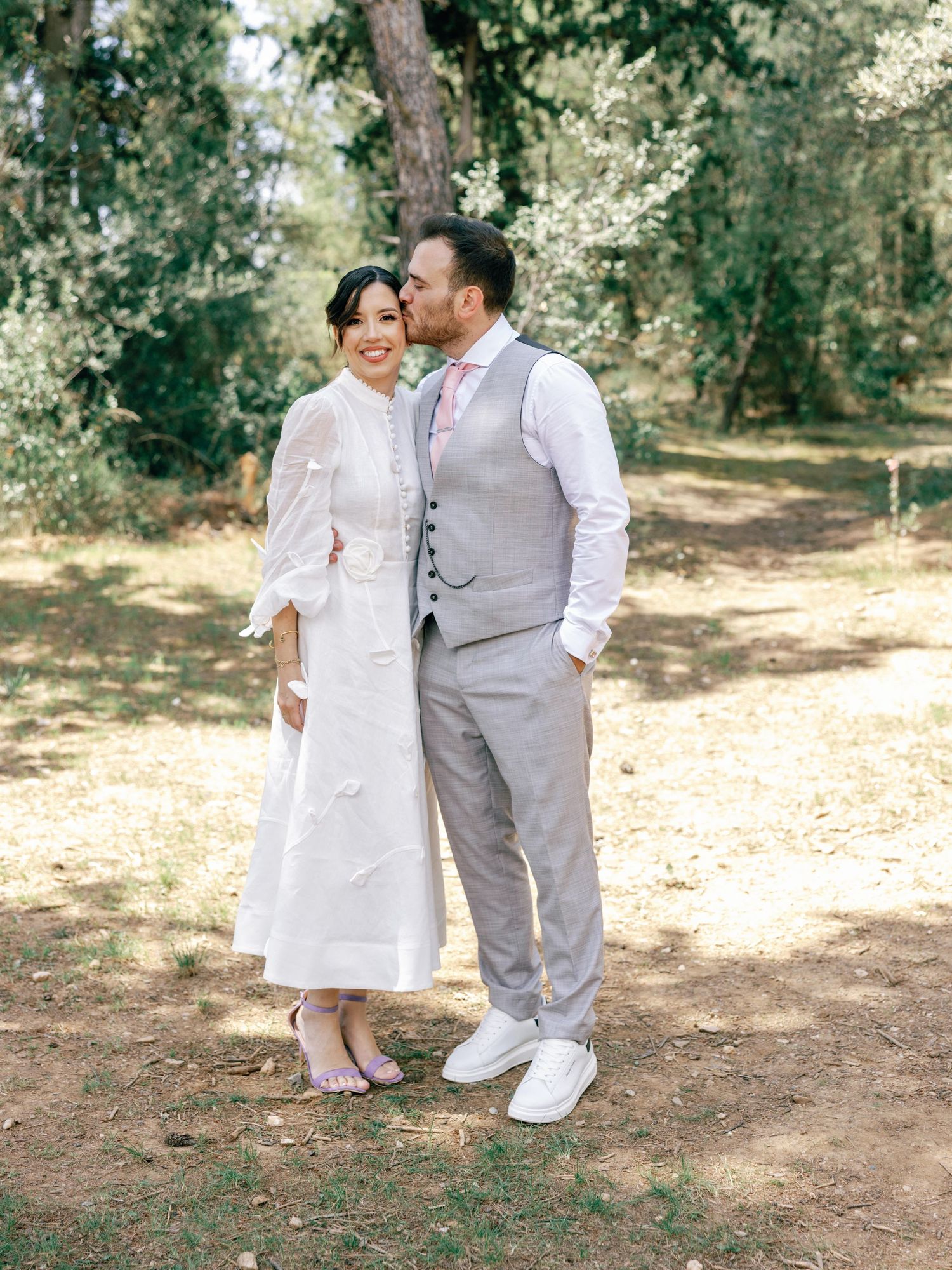 A couple shares an intimate moment together in a sunlit wooded area during their outdoor photoshoot.