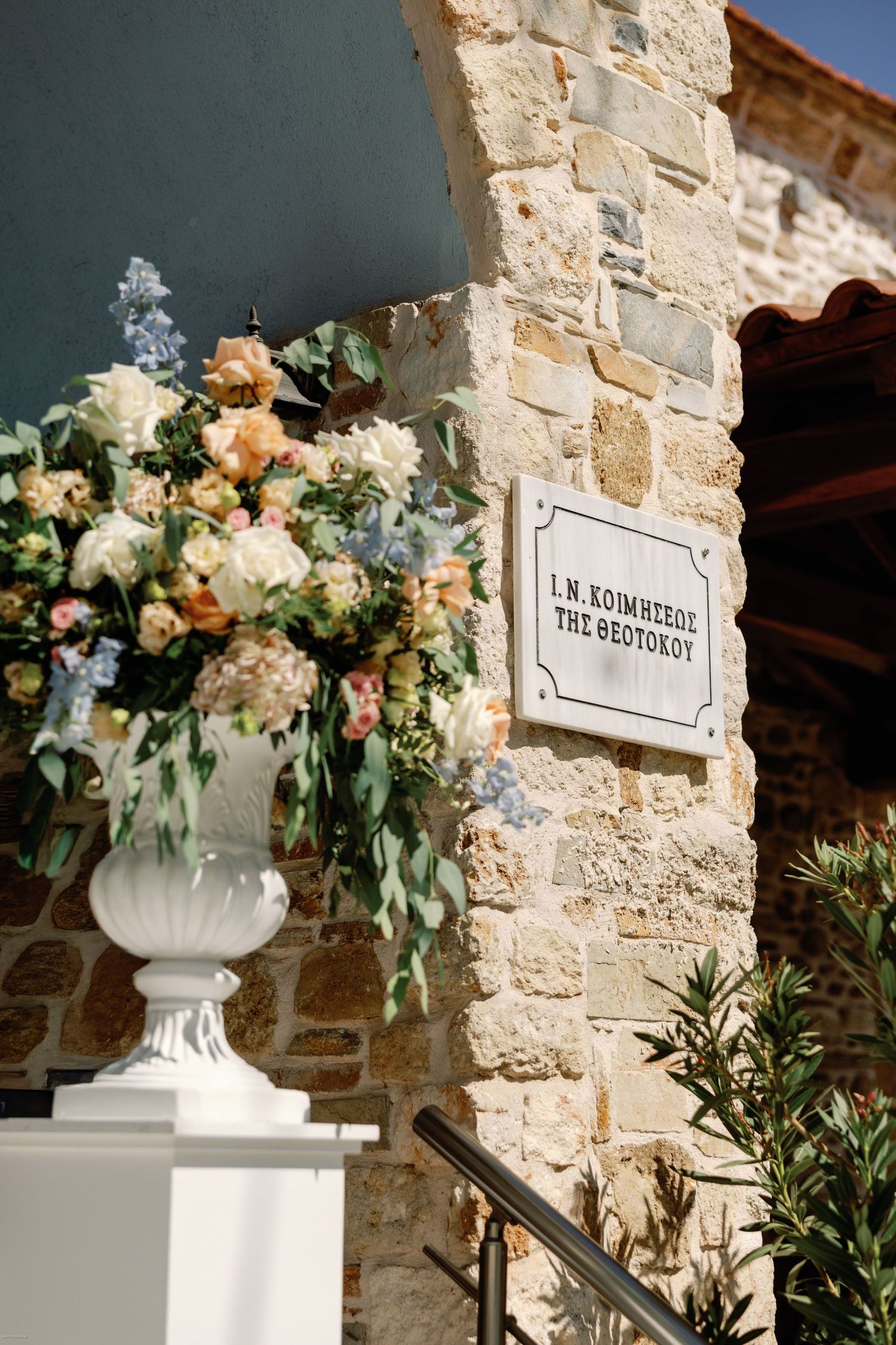 Stone wall decorated with elegant white floral arrangements in classical urns for a wedding.