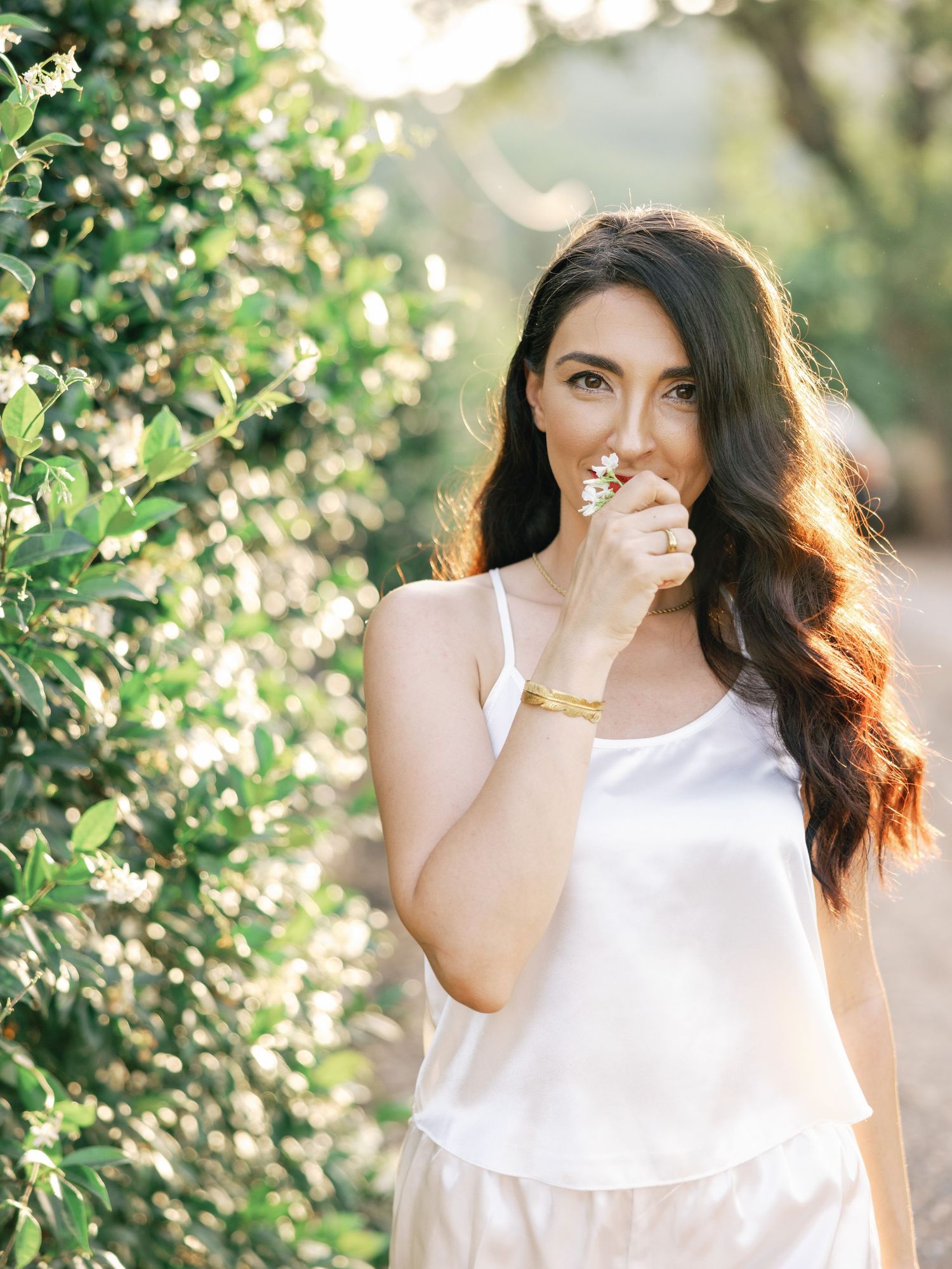 Candid portrait series in a sunlit garden with white summer dress and natural greenery backdrop.