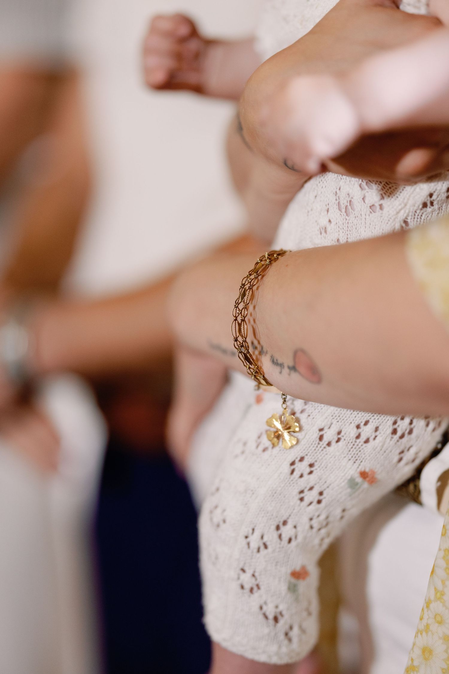 Close-up of delicate gold bracelet details against white lace fabric.
