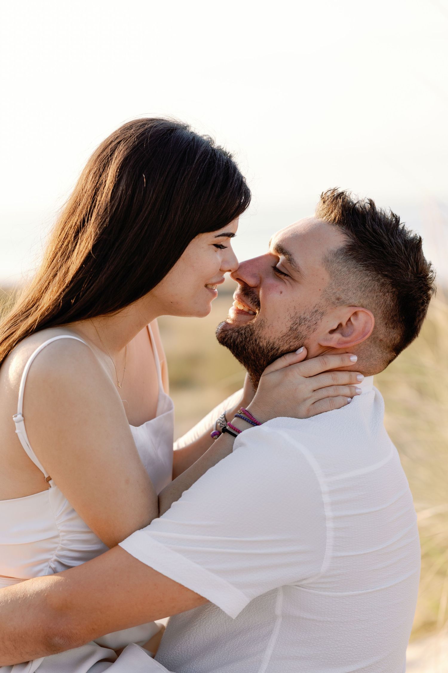 Intimate close-up shots of couple embracing and almost kissing in white outfits.