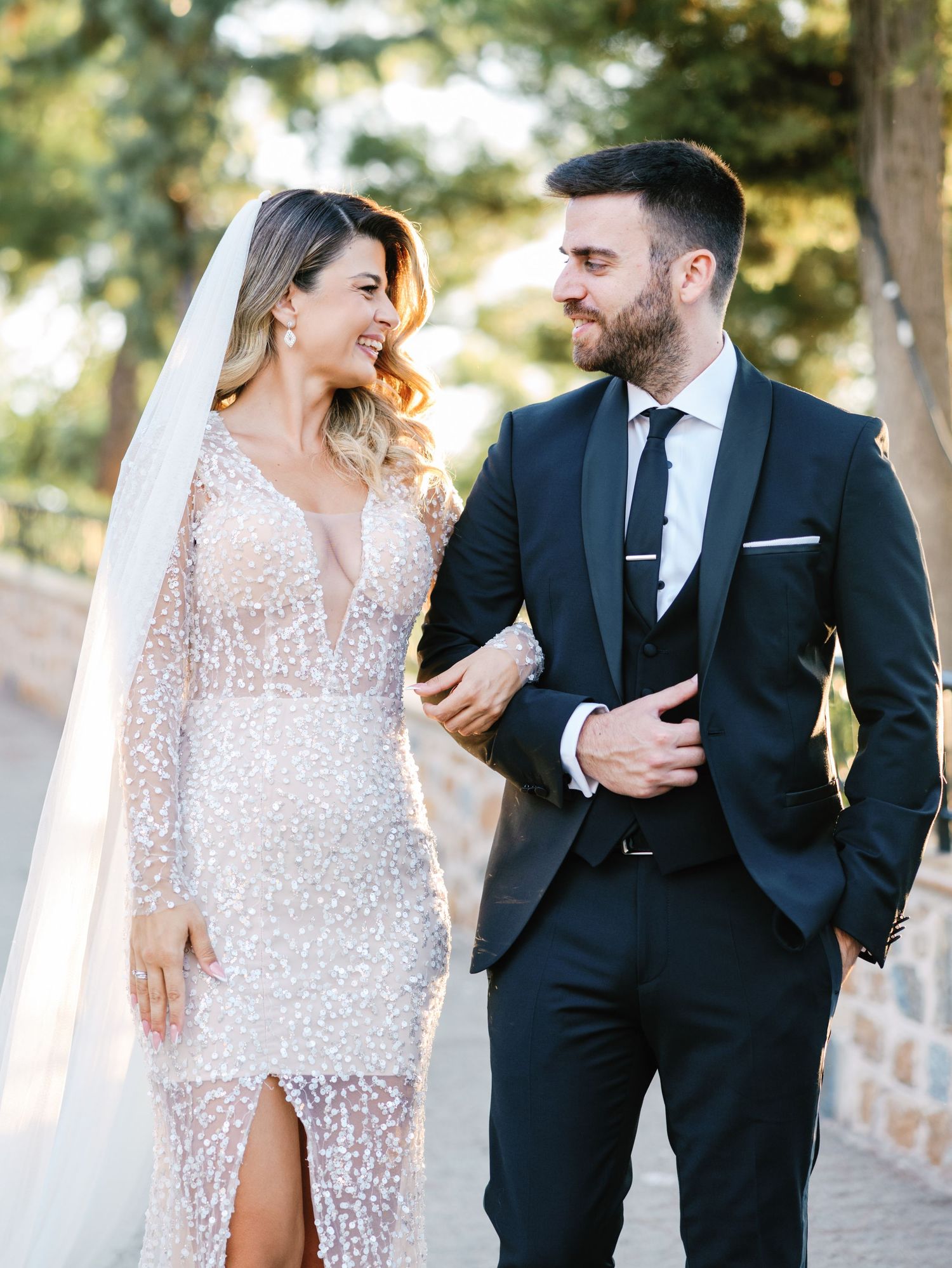 Elegant wedding couple strolls together on stone path during romantic outdoor photo session.