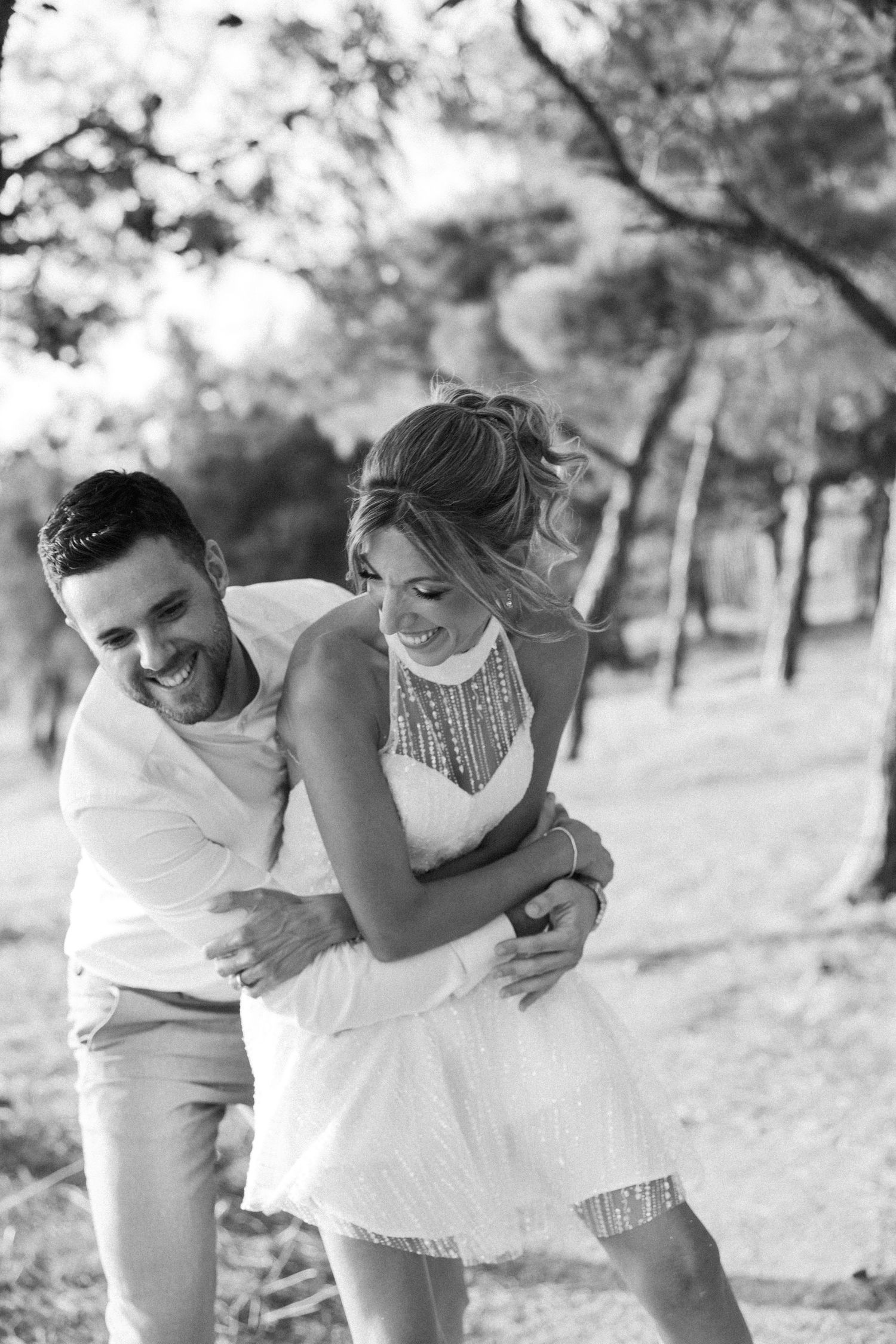 A couple shares intimate moments and laughter in black and white wedding photos.