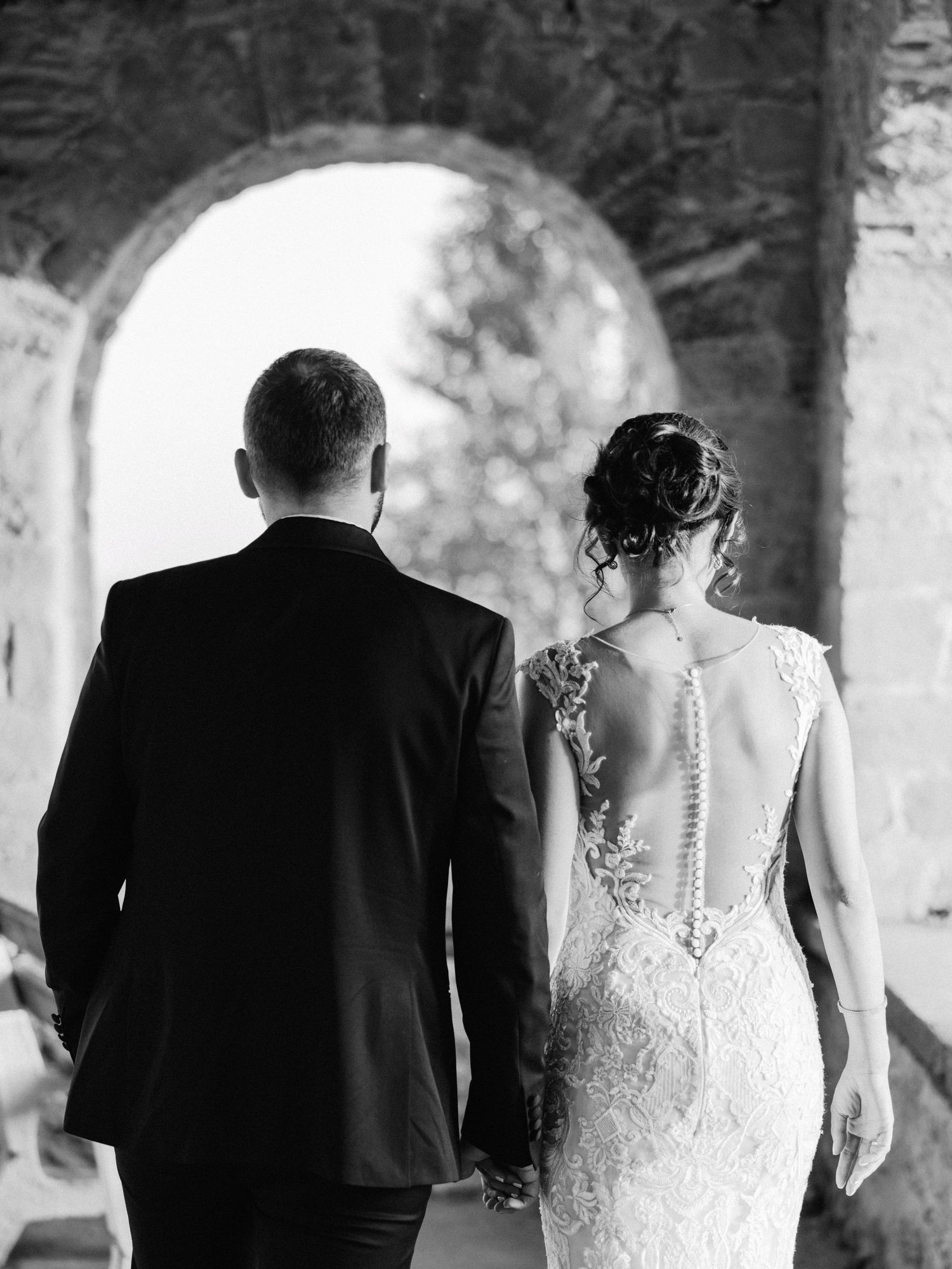 Silhouetted wedding couple sharing intimate moments under stone archways.
