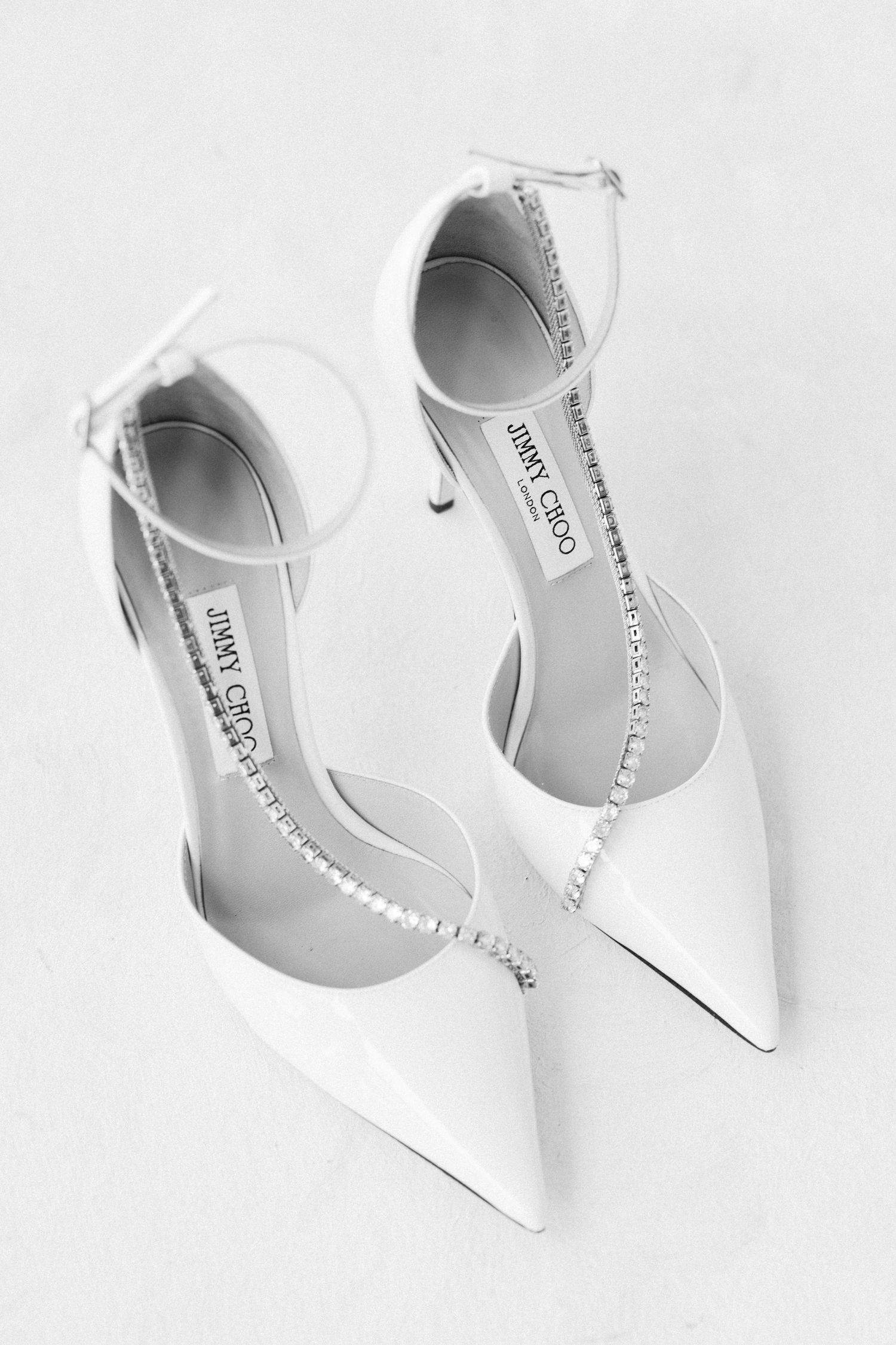 Elegant white bridal shoes arranged in different angles on light background.