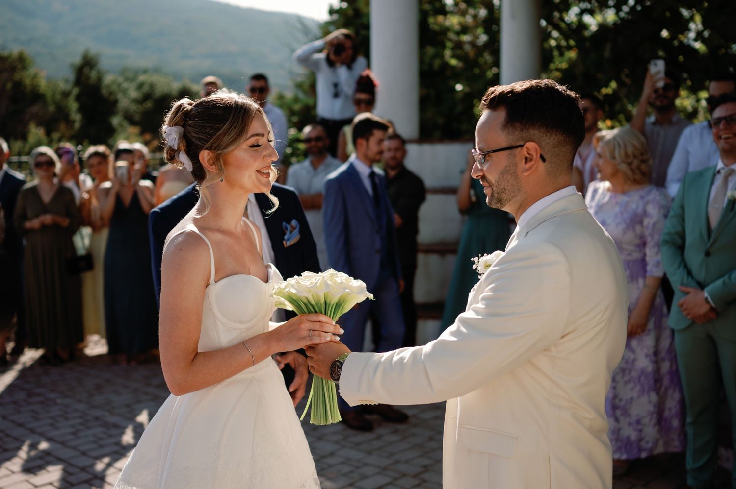 Joyful wedding celebration on an outdoor terrace with mountain views in the background.