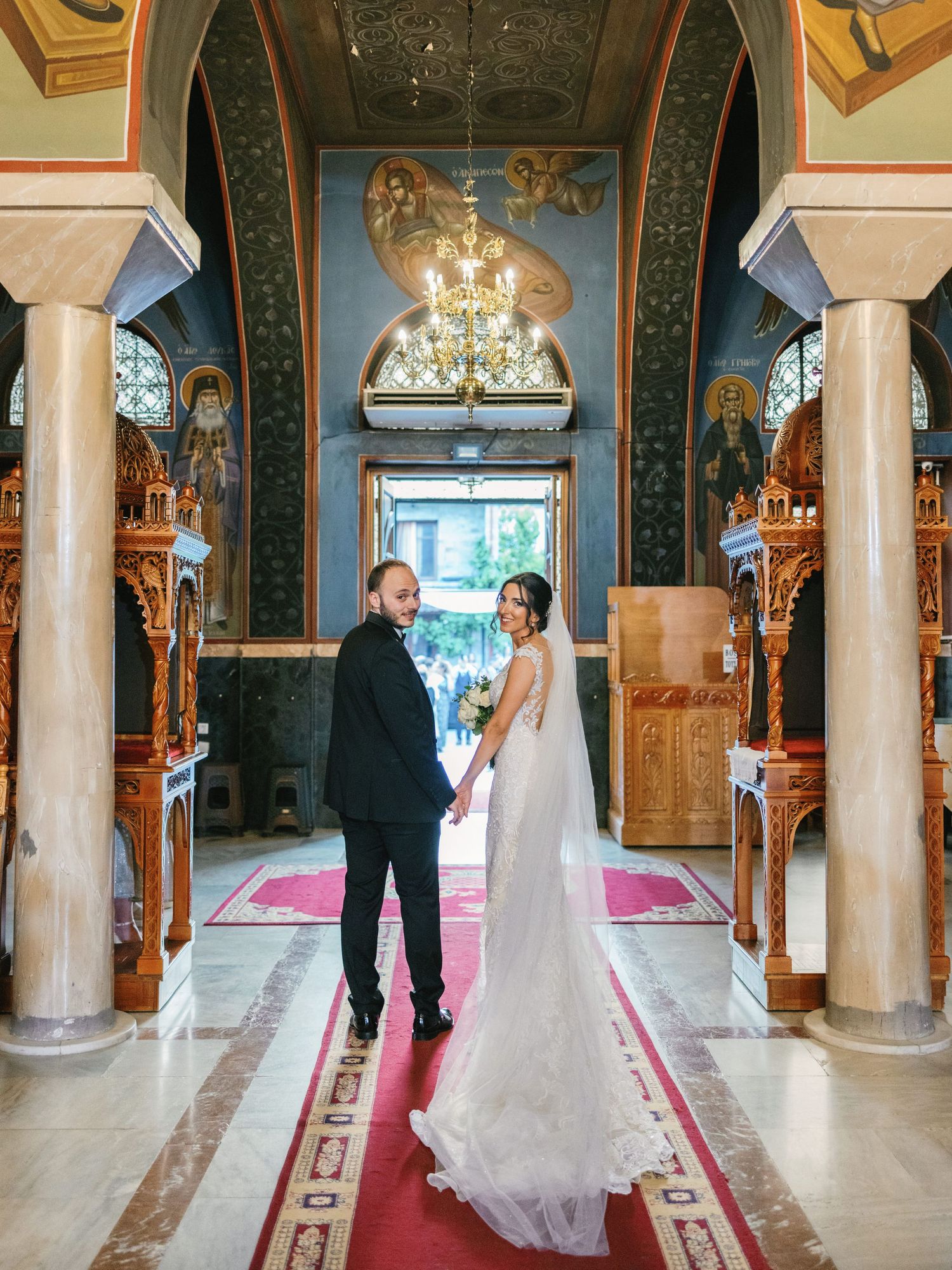 A couple shares their first dance in an elegant church interior with ornate columns and decorative details.