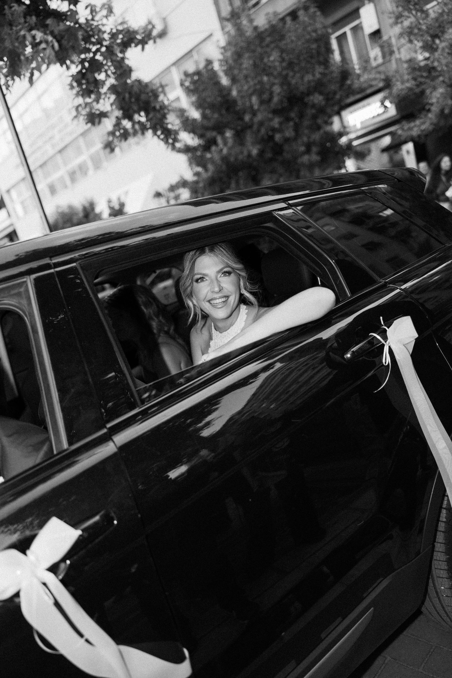 Black luxury car arrives at wedding venue with passengers inside.