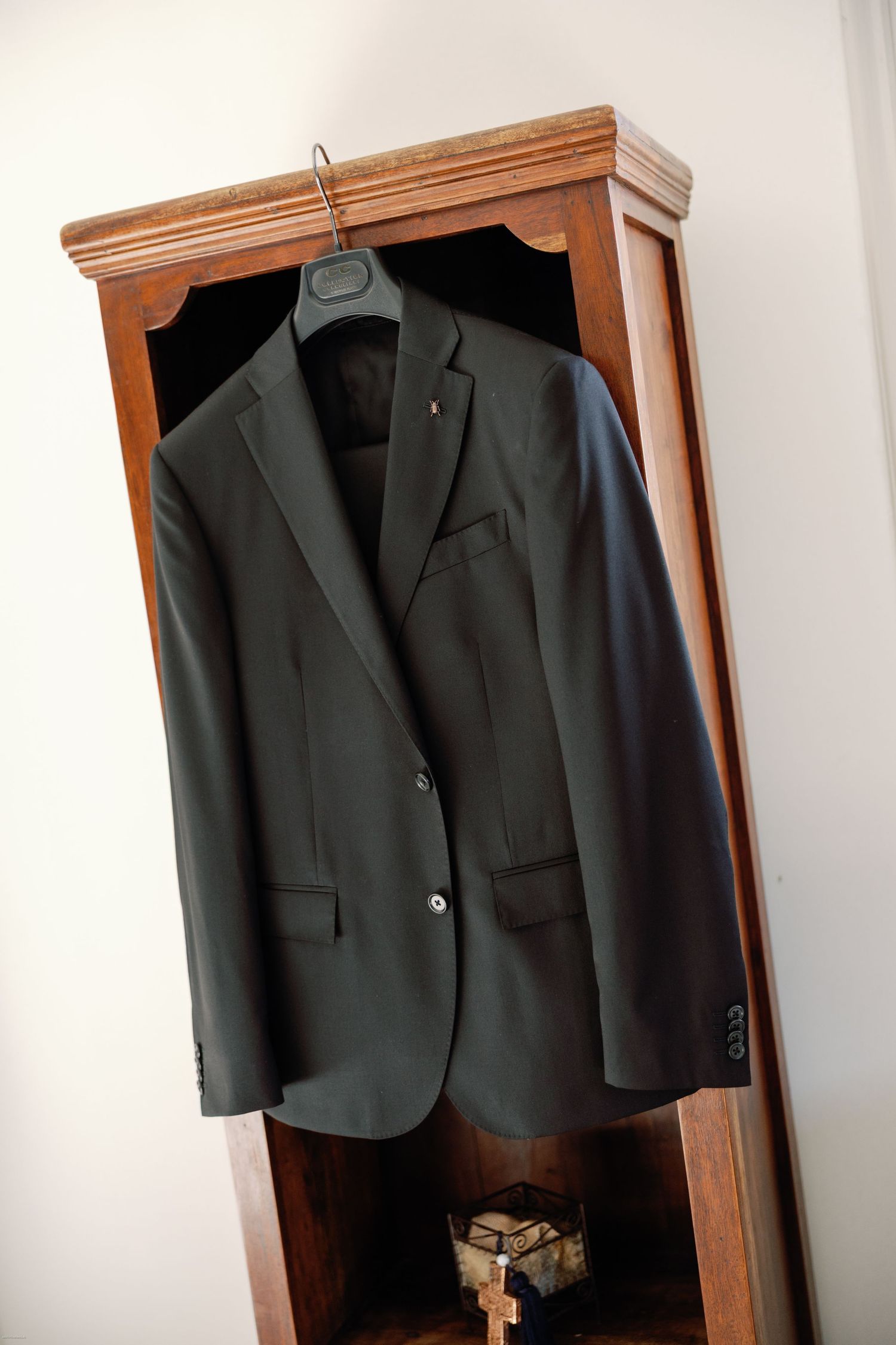 Black formal suit jackets hanging in a wooden wardrobe.