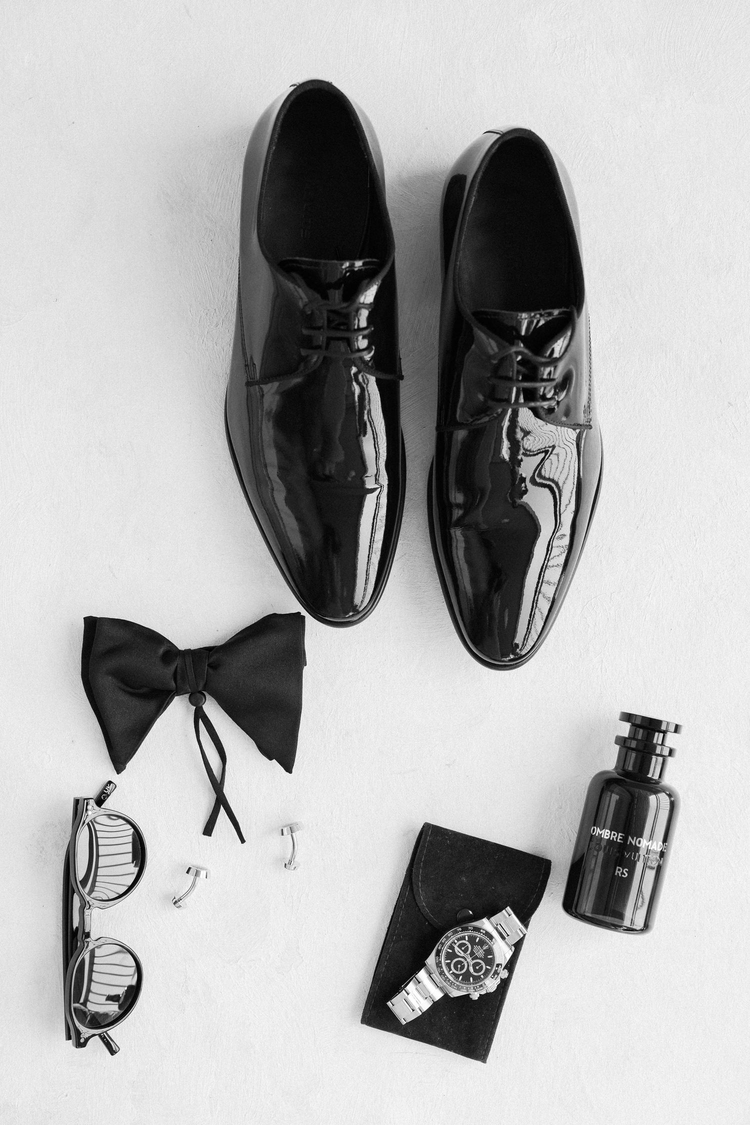 Black formal men's shoes and accessories arranged on white background.