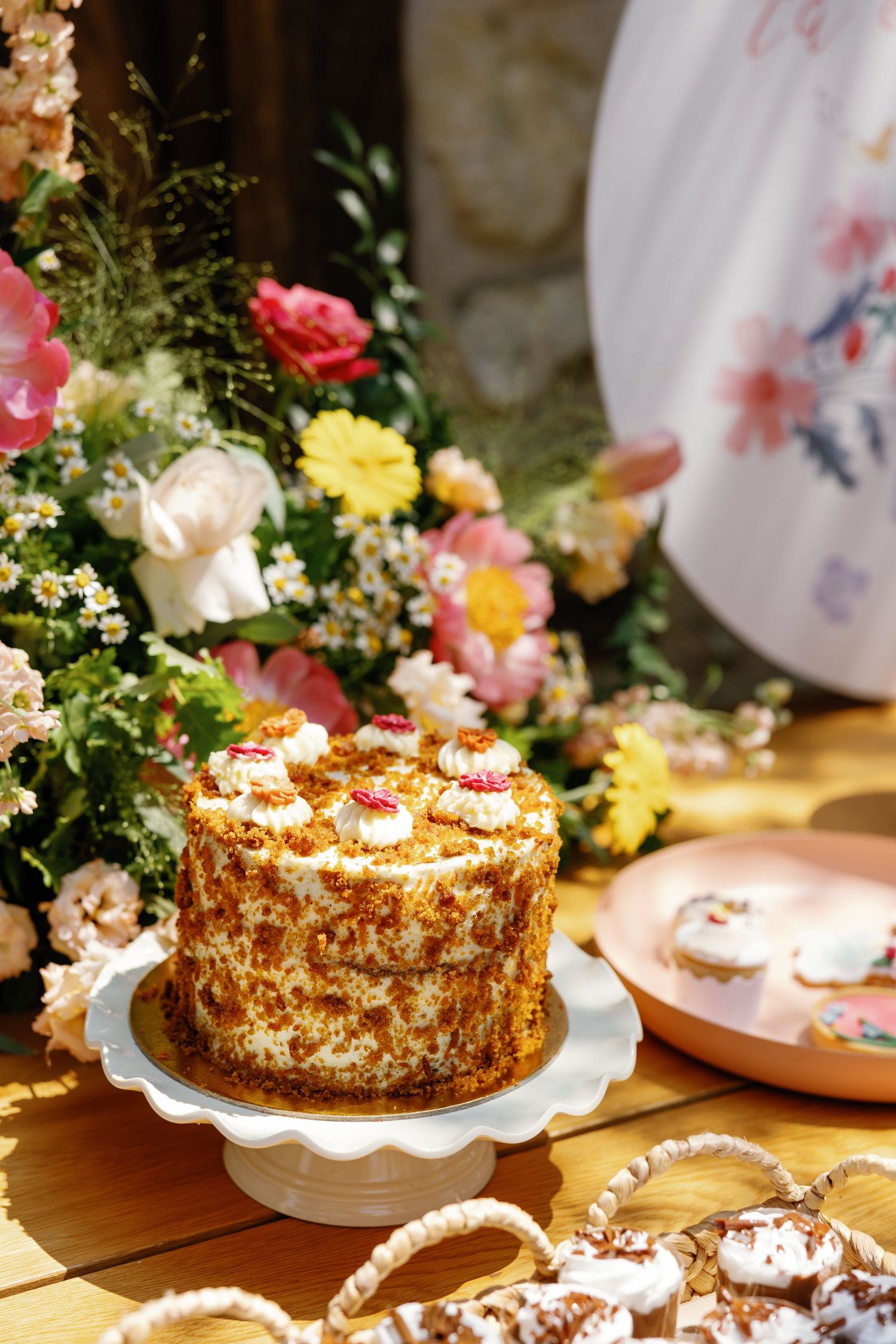 Red velvet cake decorated with flowers and surrounded by colorful floral arrangements.