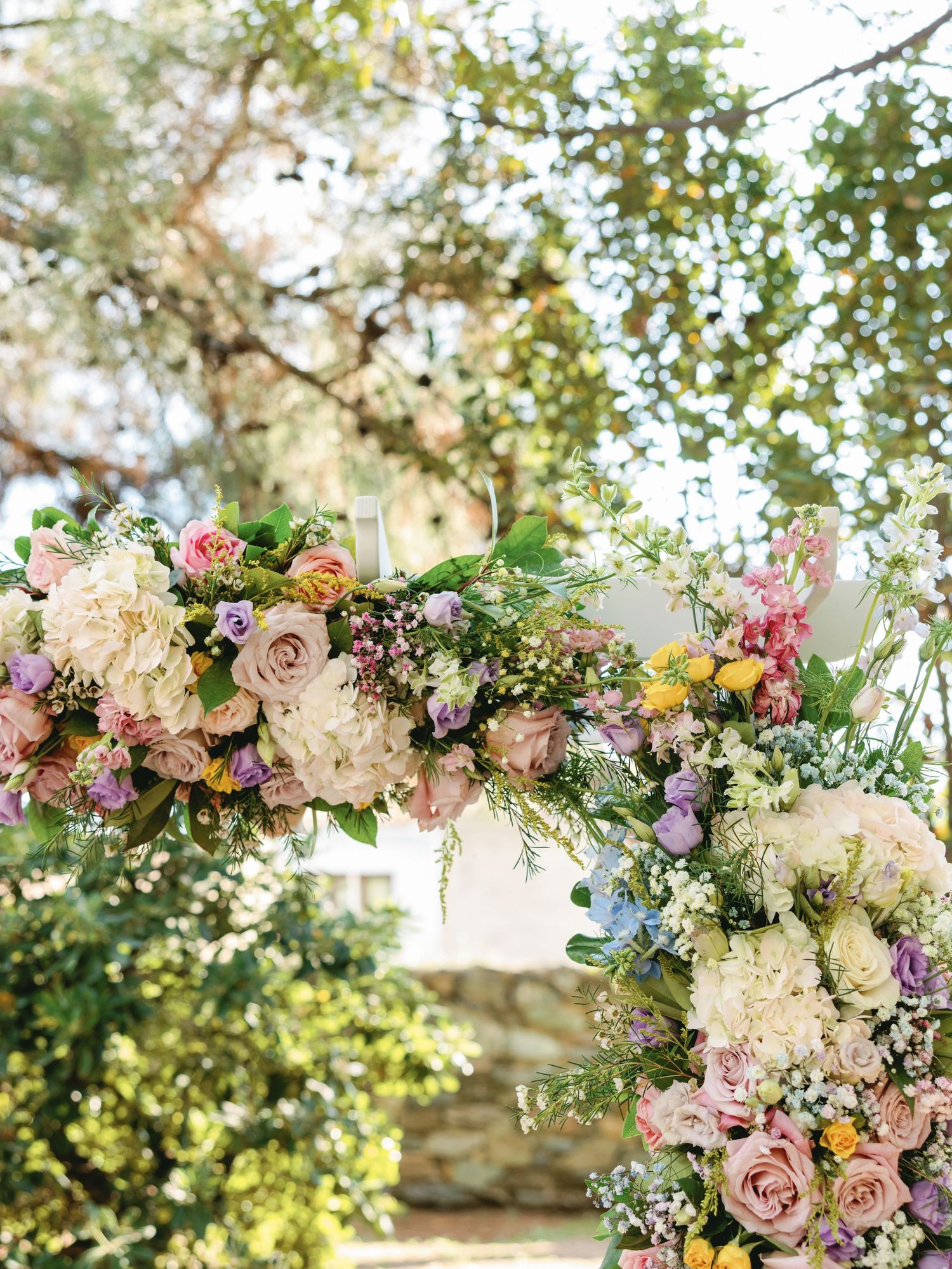 Romantic floral arch with pink roses, white hydrangeas, and mixed blooms creates an elegant outdoor wedding setting.