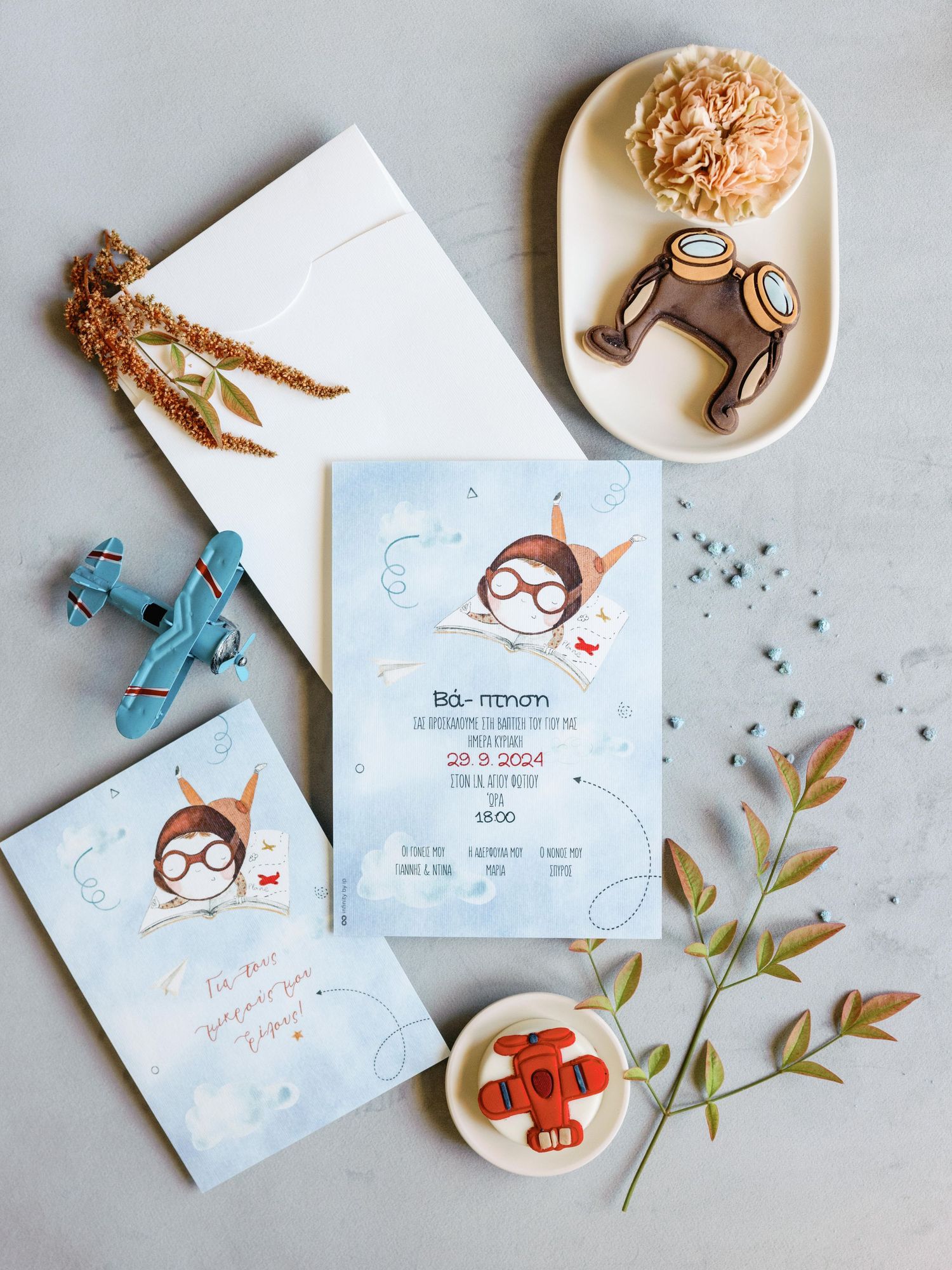 Flat lay of whimsical illustrated party invitations with decorative elements and cookies on a light gray background.