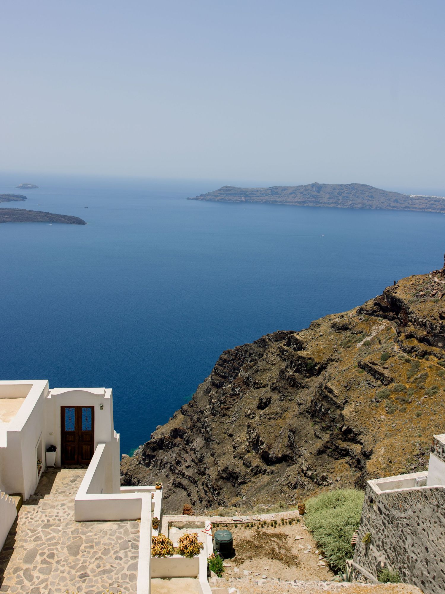 White buildings and stone pathways along the cliffs of Santorini with ocean views.