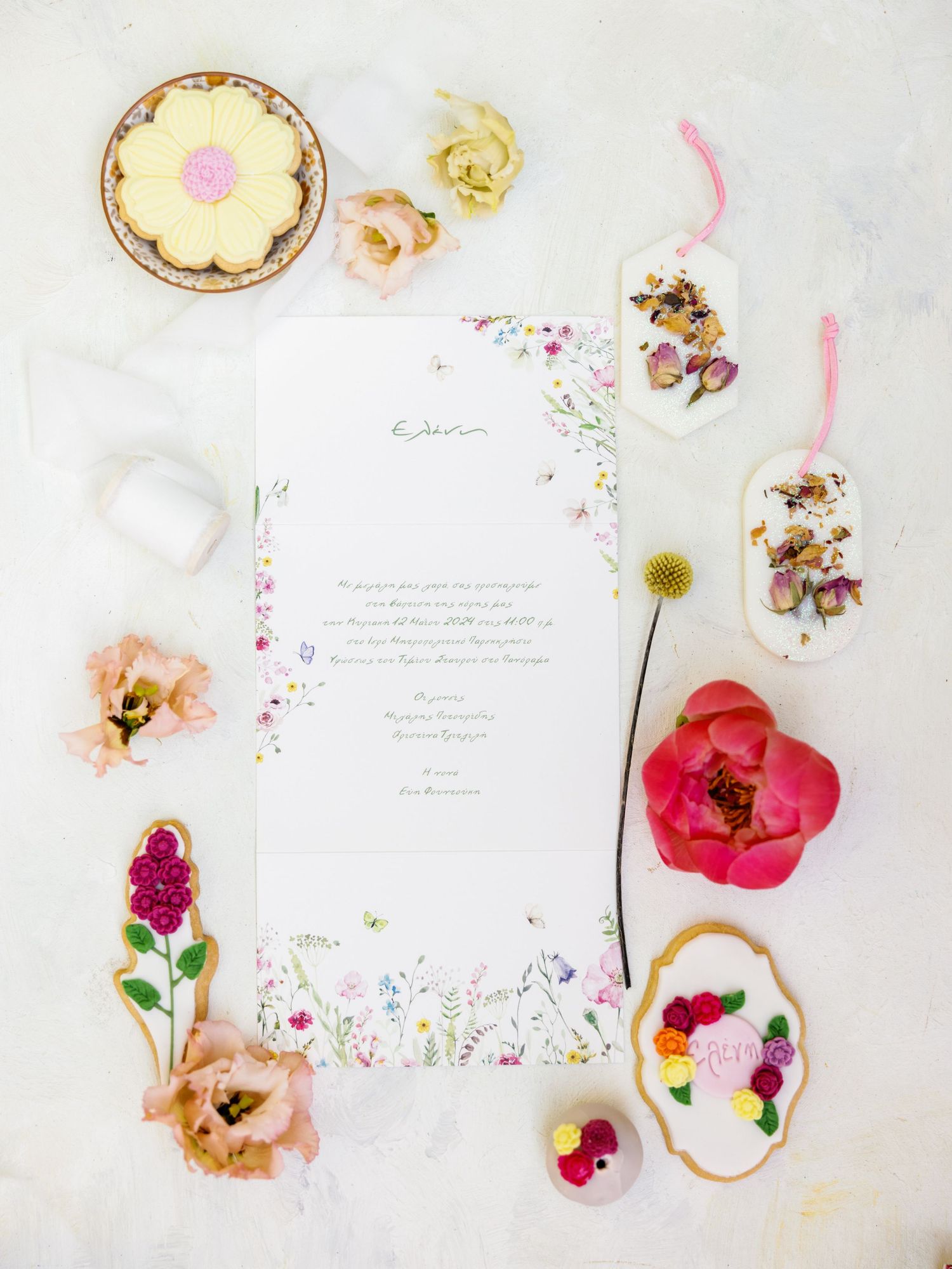 Delicate floral arrangement with pink and red poppies scattered among white paper and vintage decor on a light background.