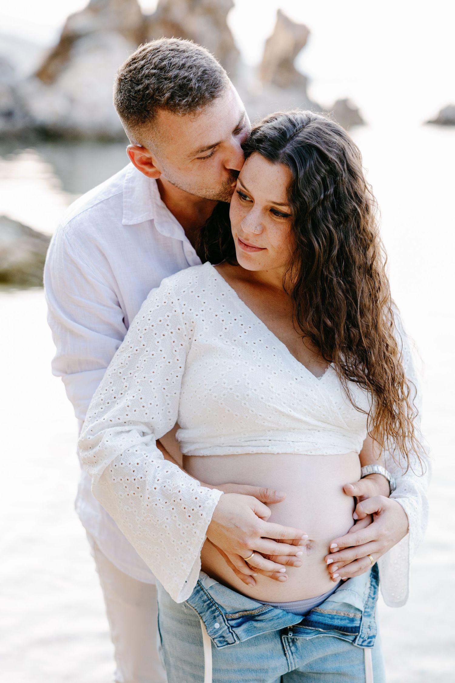 Tender maternity moments captured in soft lighting on the beach.
