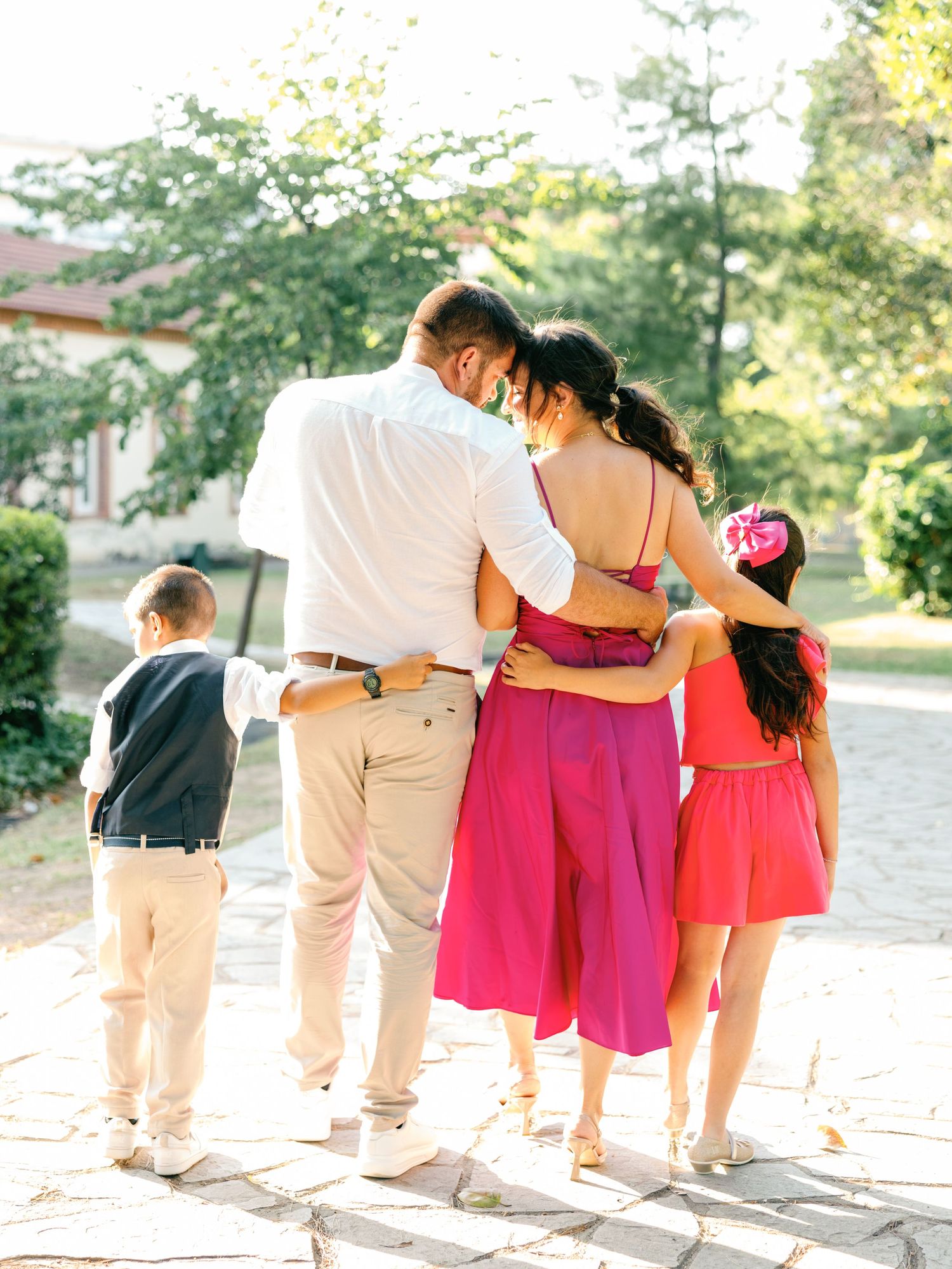 A family in coordinated outfits walking together on a sunny path with trees in the background.
