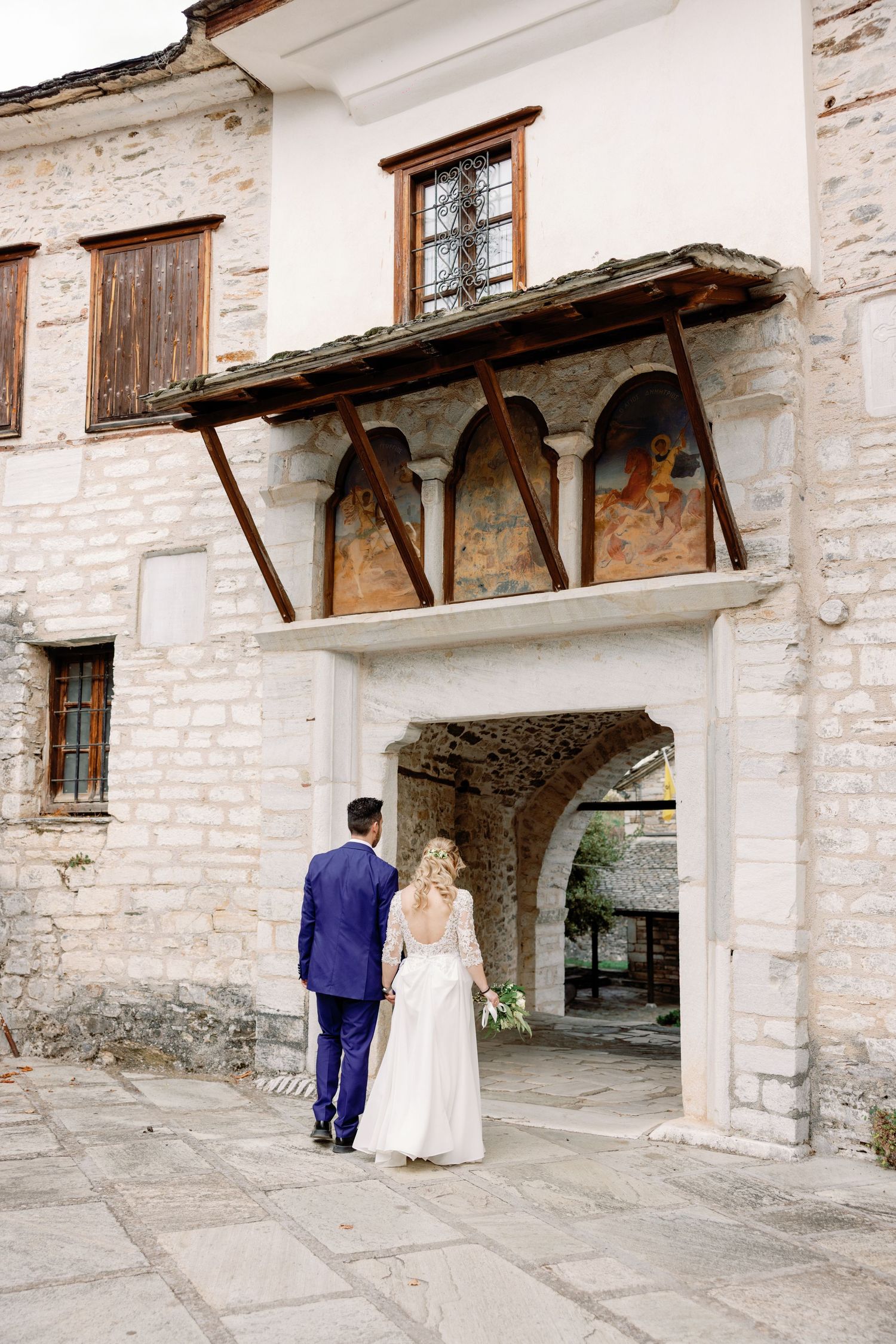 Wedding couple poses under rustic stone archways at historic venue.