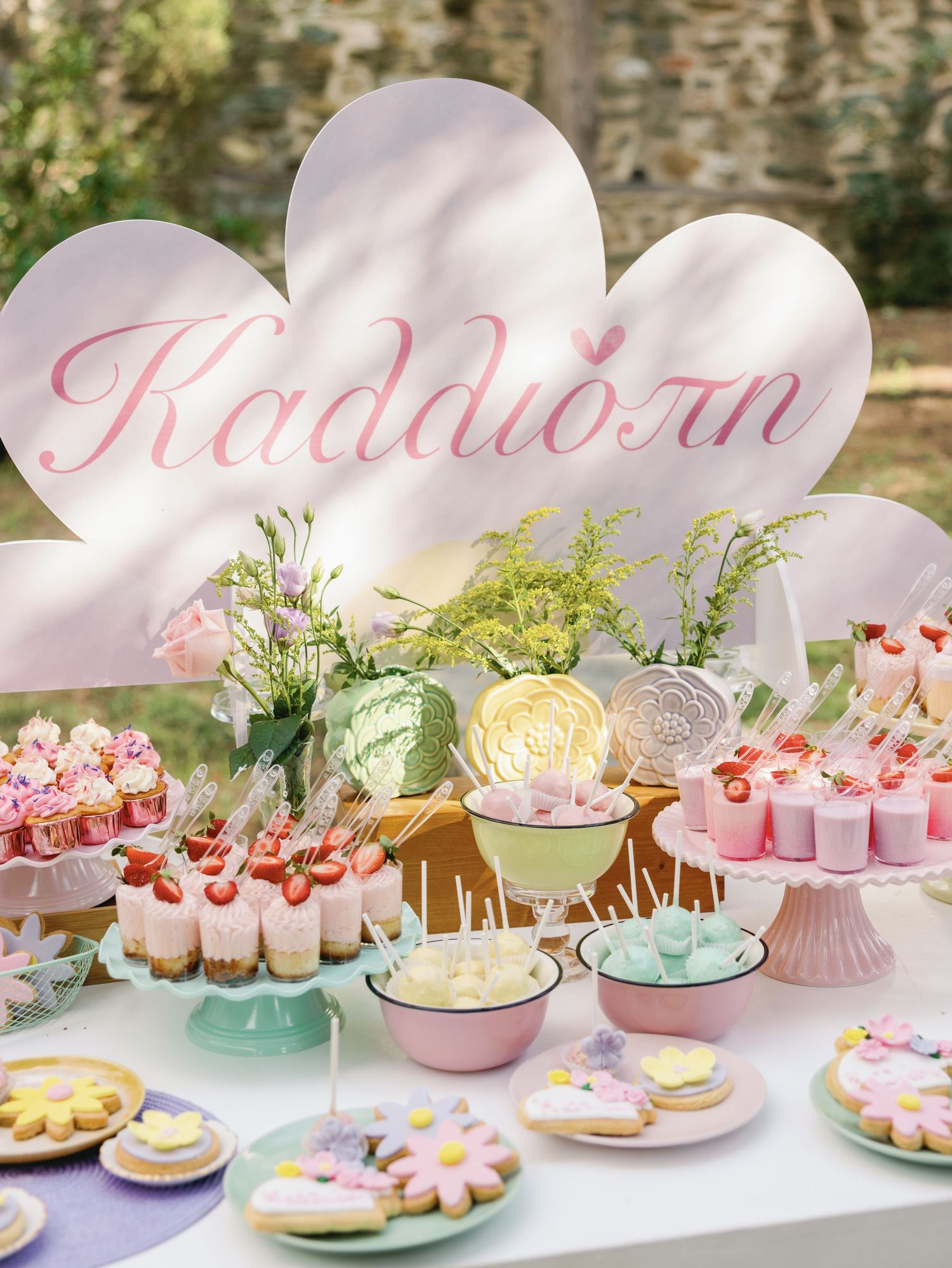 A pastel pink and mint dessert table with macarons, cookies and cupcakes decorated with heart balloons and floral accents.