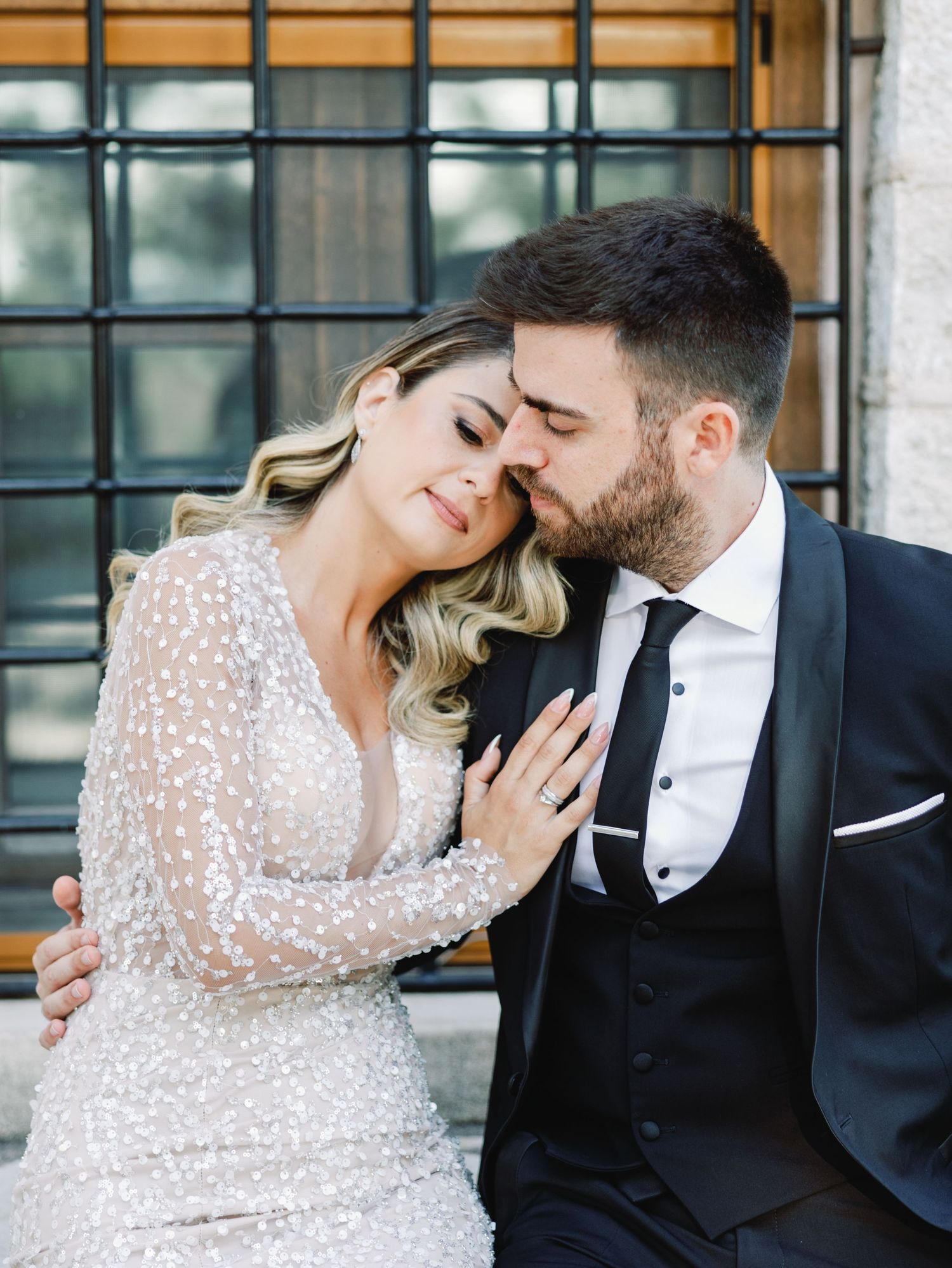 Elegant couple in wedding attire sharing intimate moments against industrial backdrop.