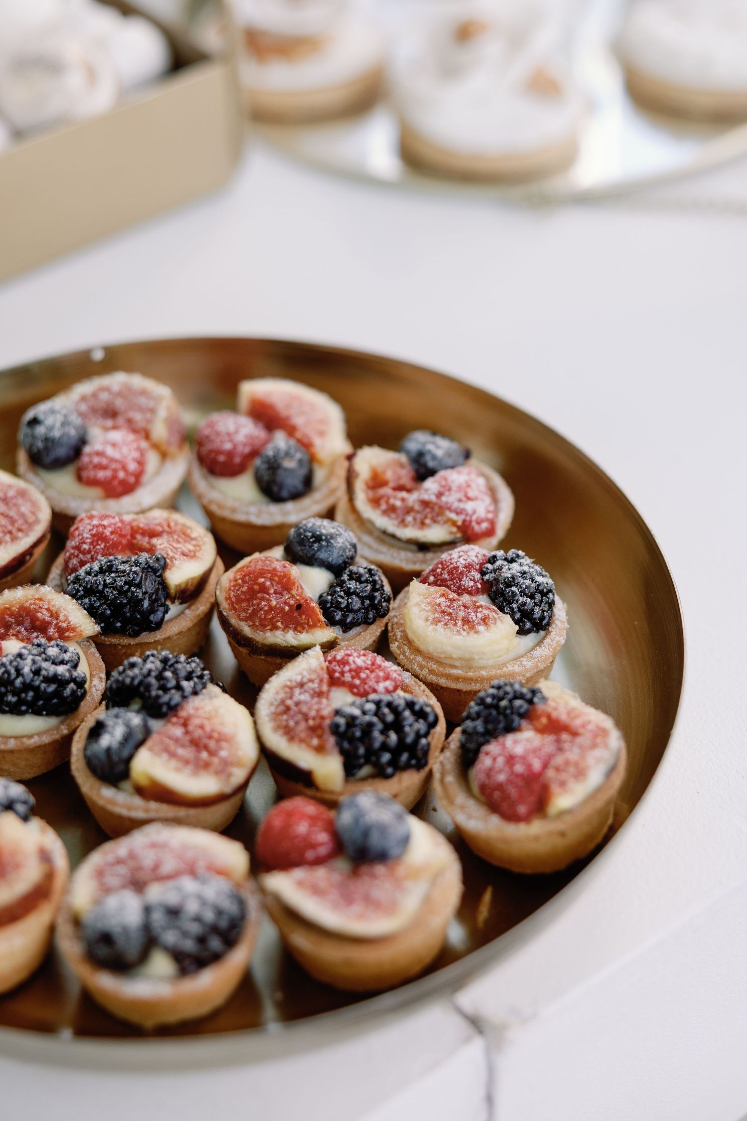 Elegant dessert plate with fresh figs and berries arranged on tarts.