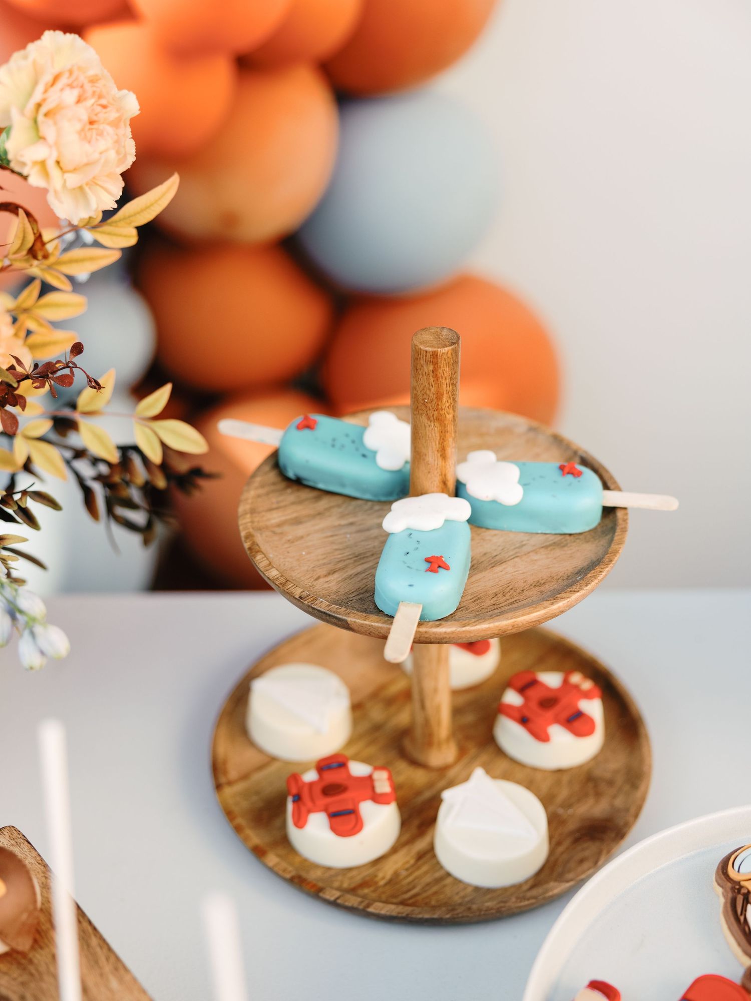 Rustic wooden serving platter displaying delicate mini desserts with blue and red decorative toppings.