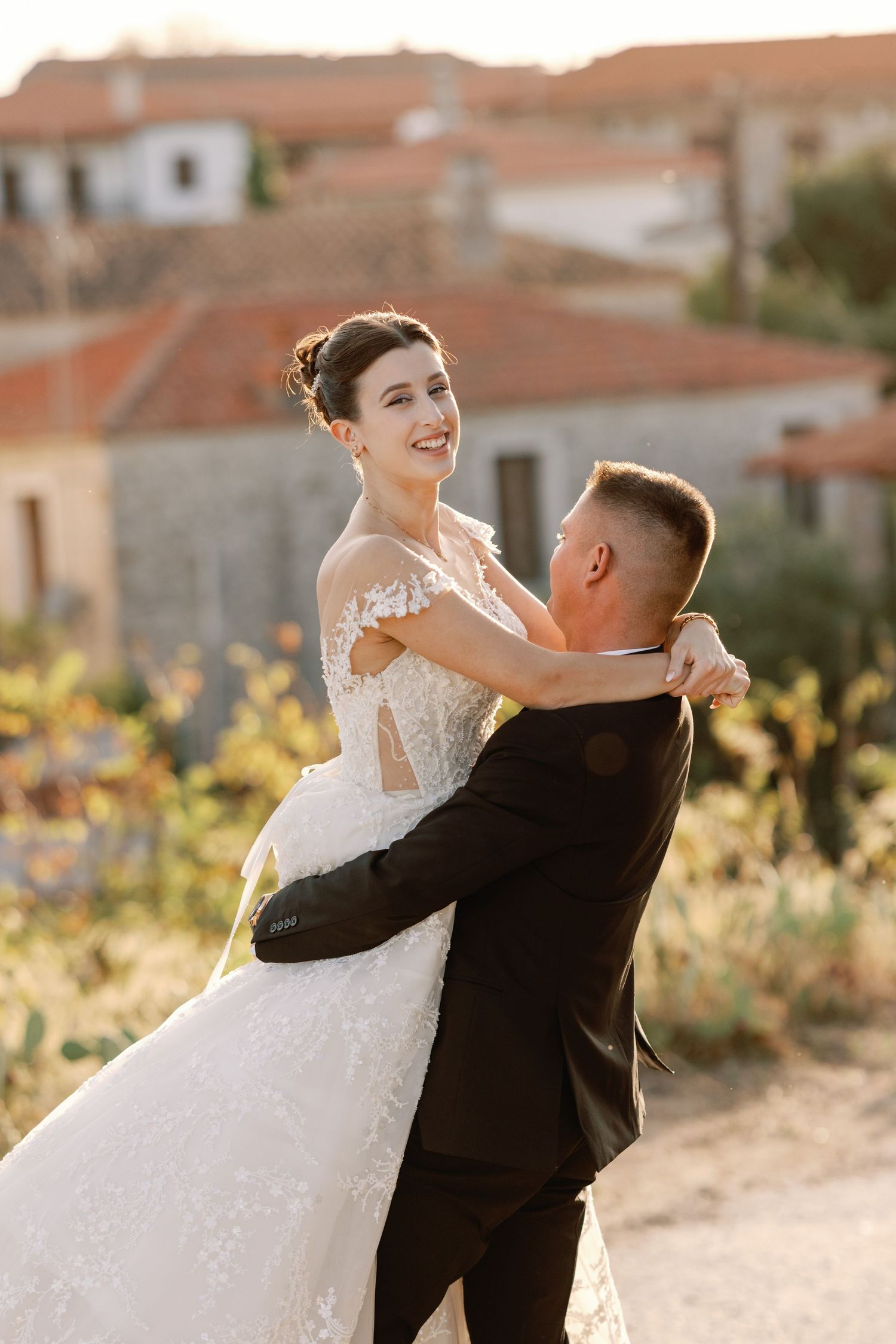 Bride and groom share playful moments against a sunset backdrop in a Mediterranean setting.