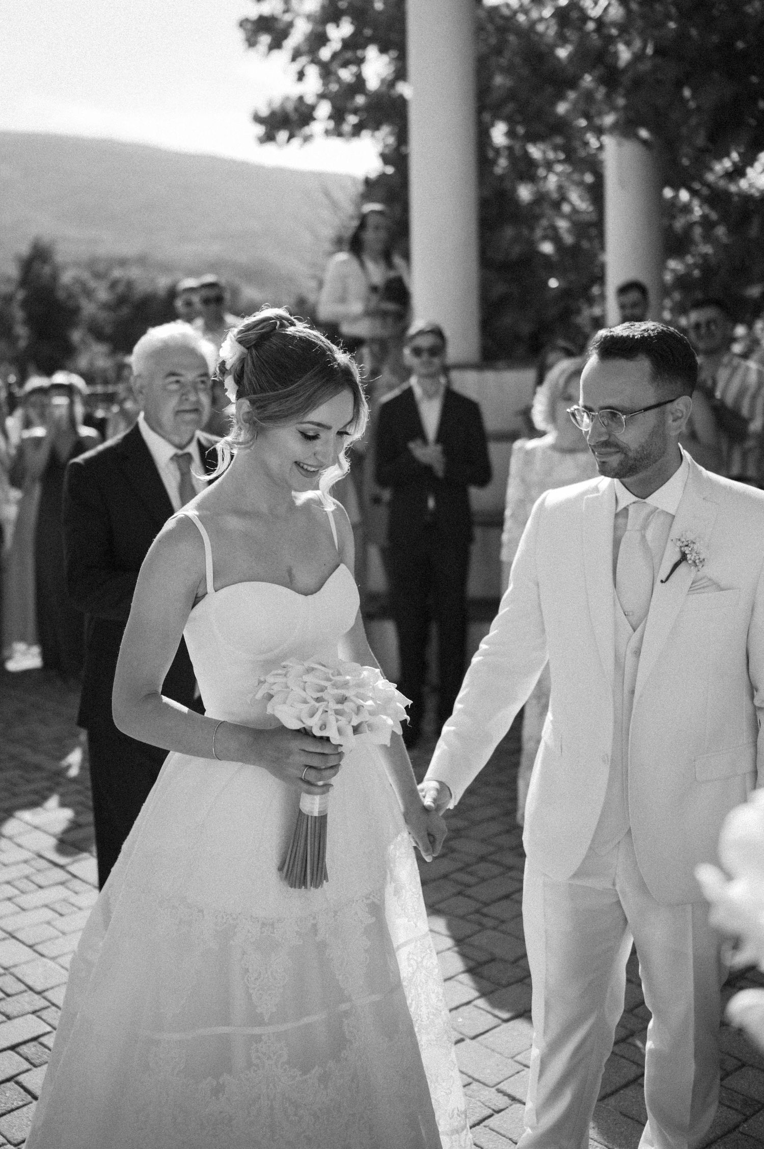 Wedding couple dancing together under elegant white columns during outdoor reception celebration.