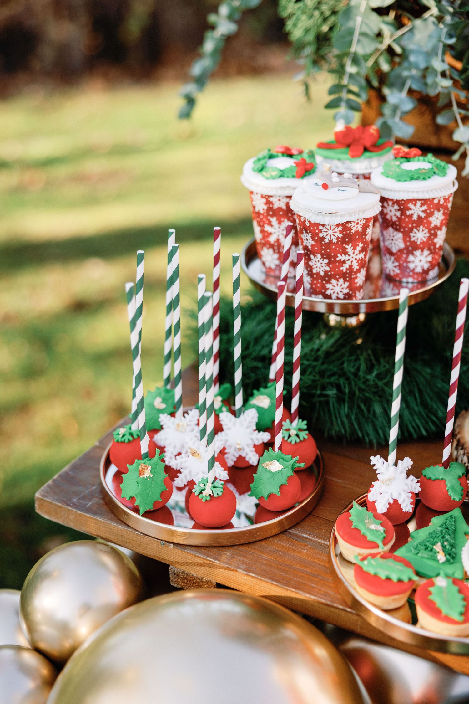 Christmas cake pops decorated with red and white snowflake patterns displayed on wooden stands with striped straws.