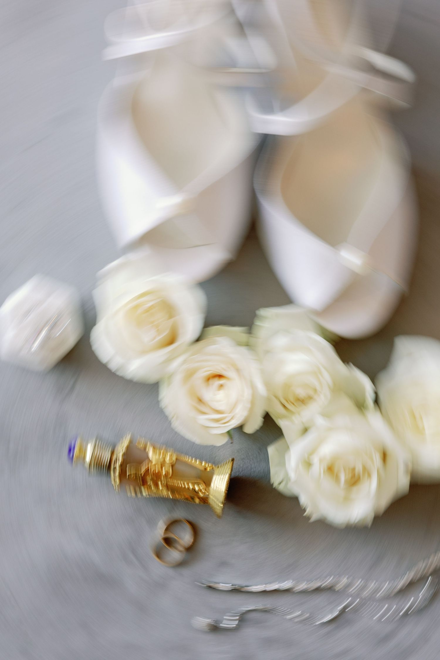 Delicate white roses and wedding rings arranged on a light surface with soft focus.