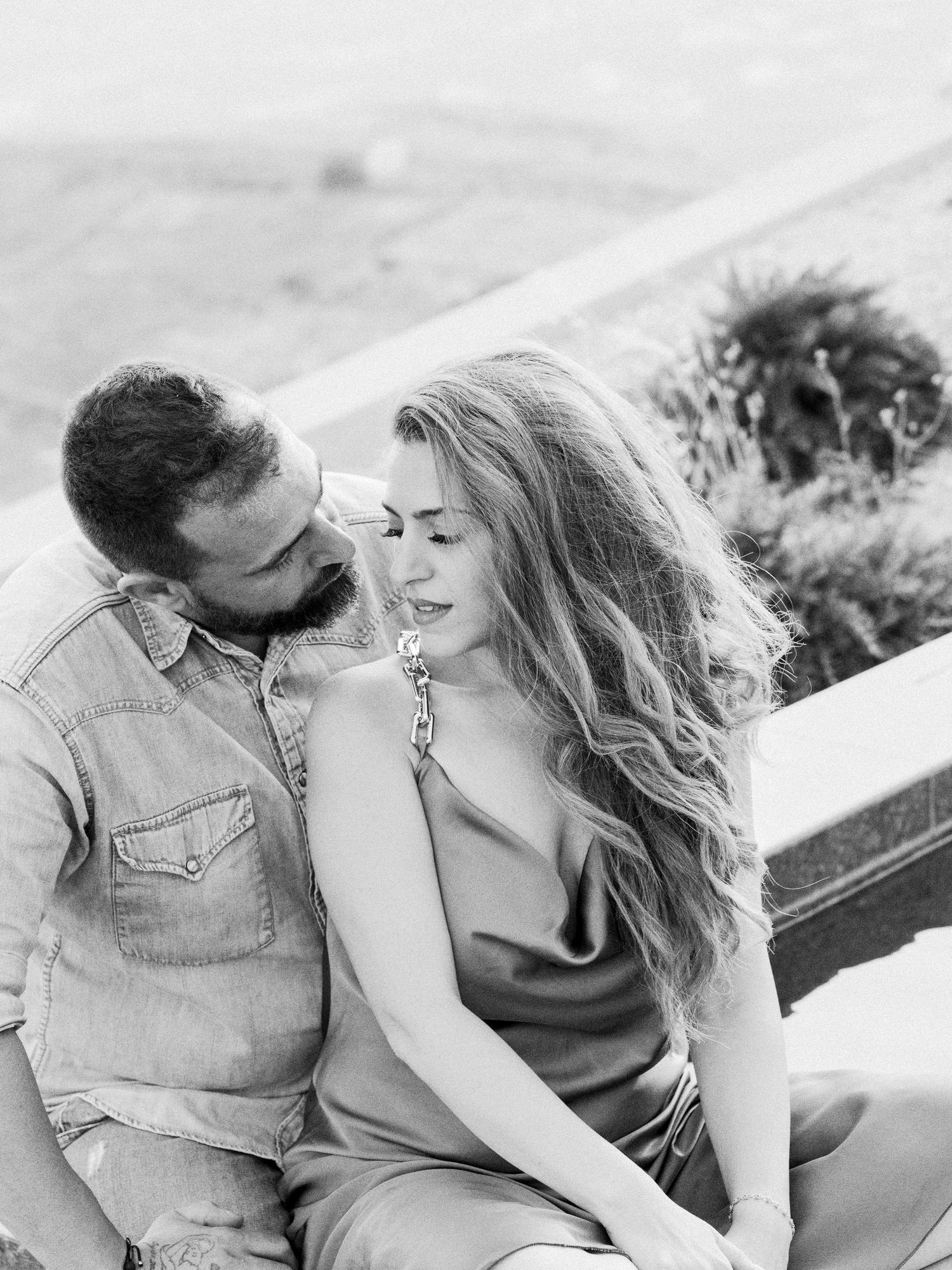 Black and white portrait of couple embracing on scenic overlook.