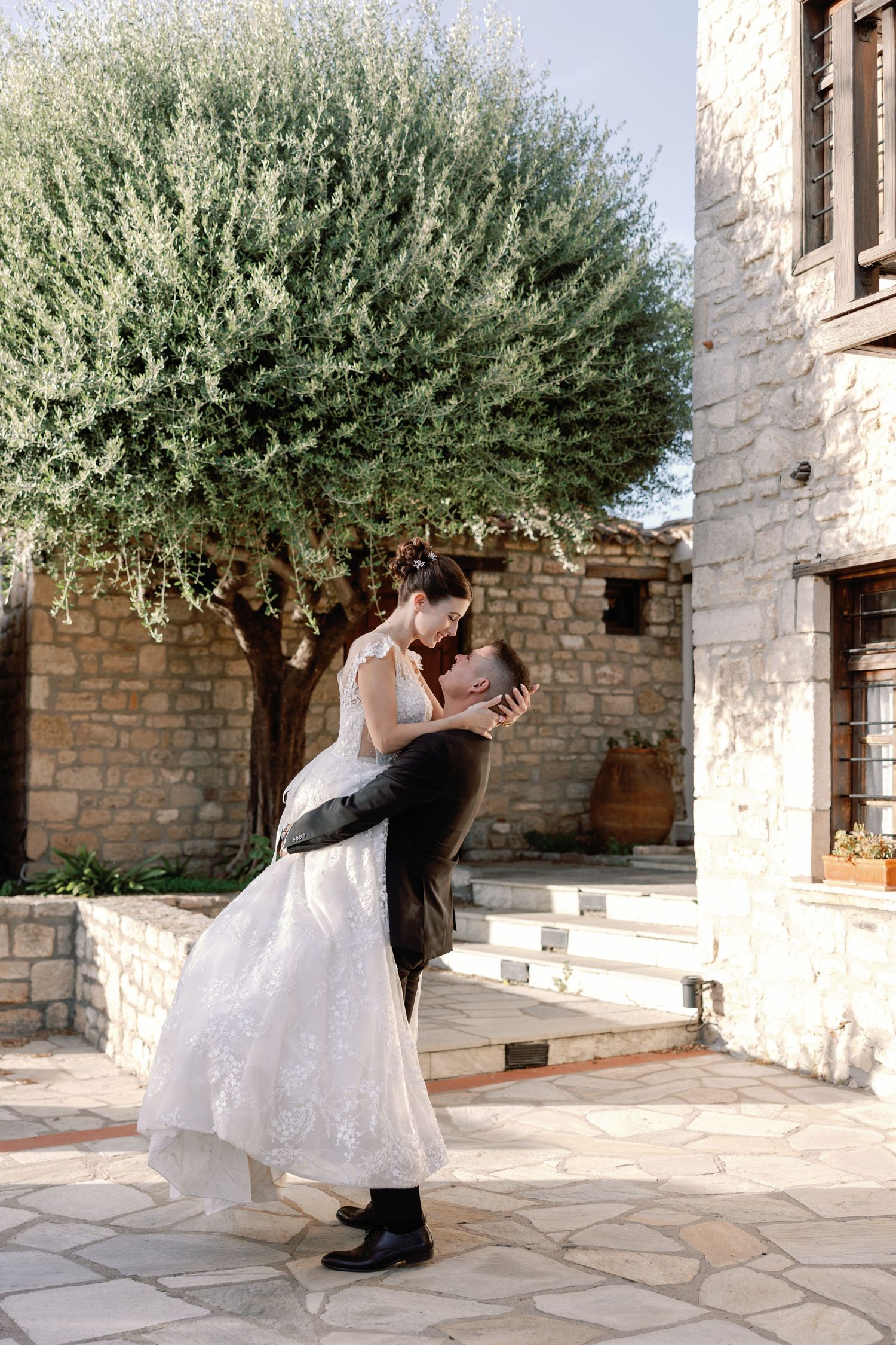 Wedding scene in a Mediterranean courtyard with stone walls and olive trees.
