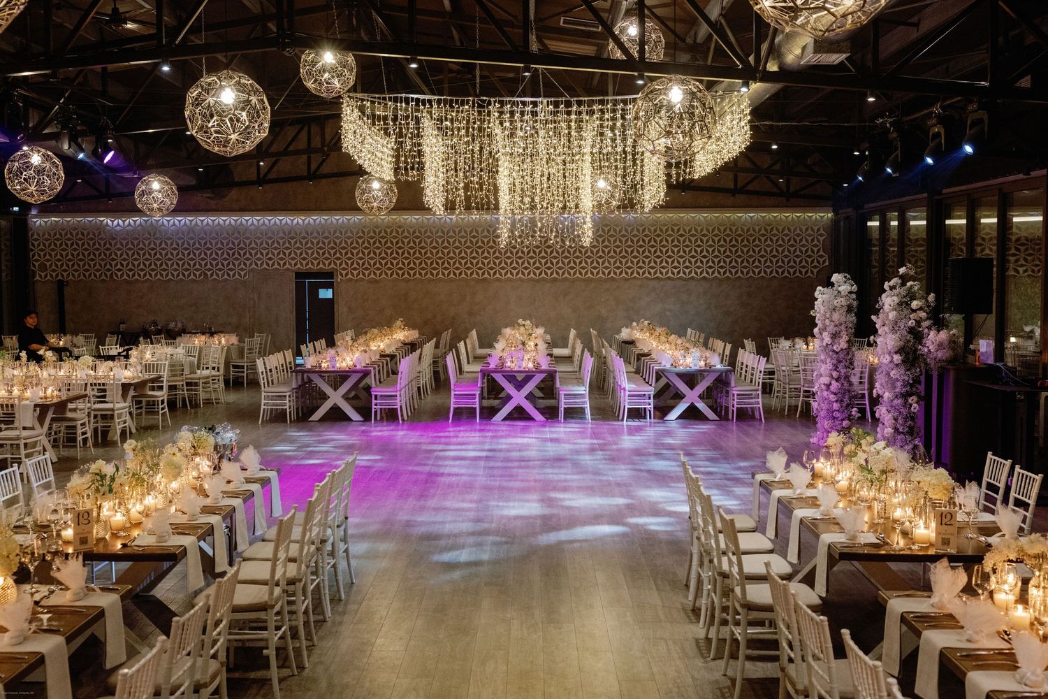 Elegant wedding reception venue with purple lighting and crystal chandeliers.