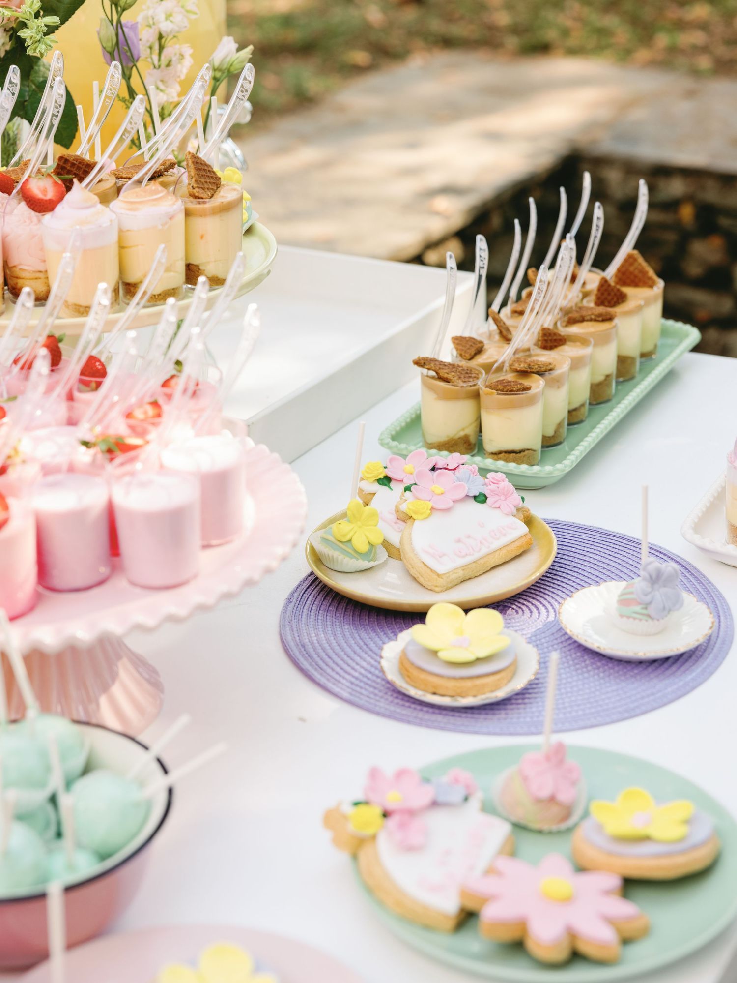 Elegant pastel dessert display featuring pink and mint green macarons, cookies, and delicate pastries on decorative plates.