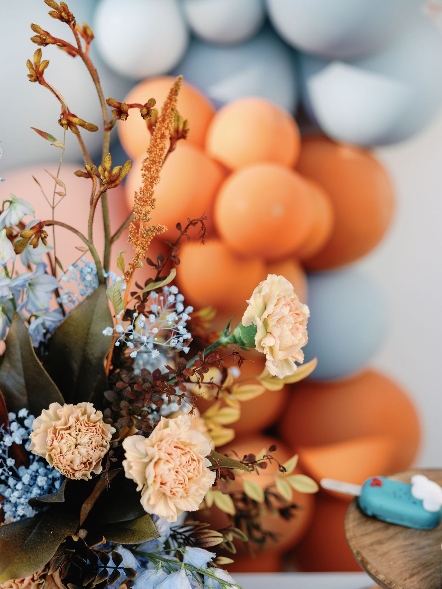 Delicate peach carnations and blue forget-me-nots create a soft floral arrangement with dreamy bokeh background effect.
