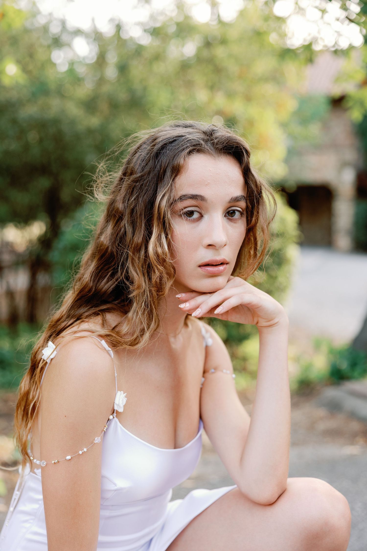Candid outdoor photoshoot featuring natural poses in a white top with garden scenery.
