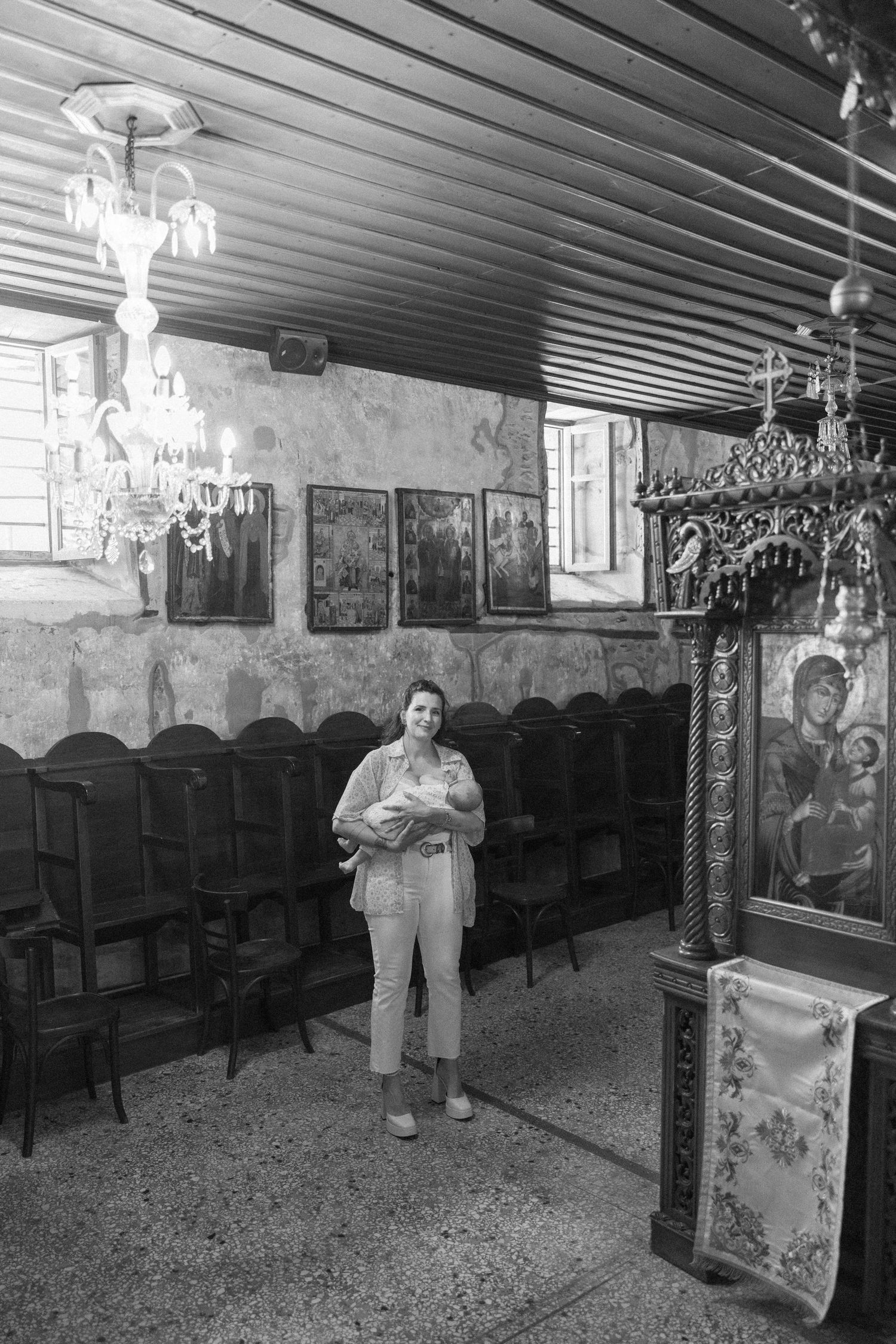Black and white photo of historic church interior with wooden chairs and religious artwork.