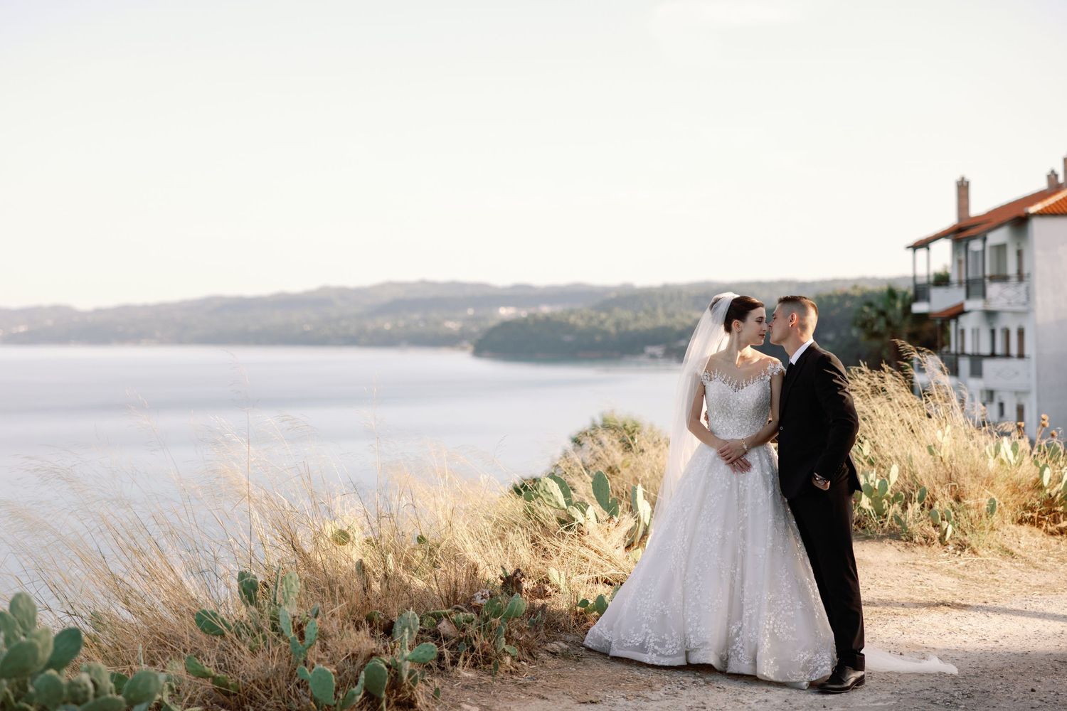 Romantic seaside wedding portraits with couple silhouetted against ocean view.