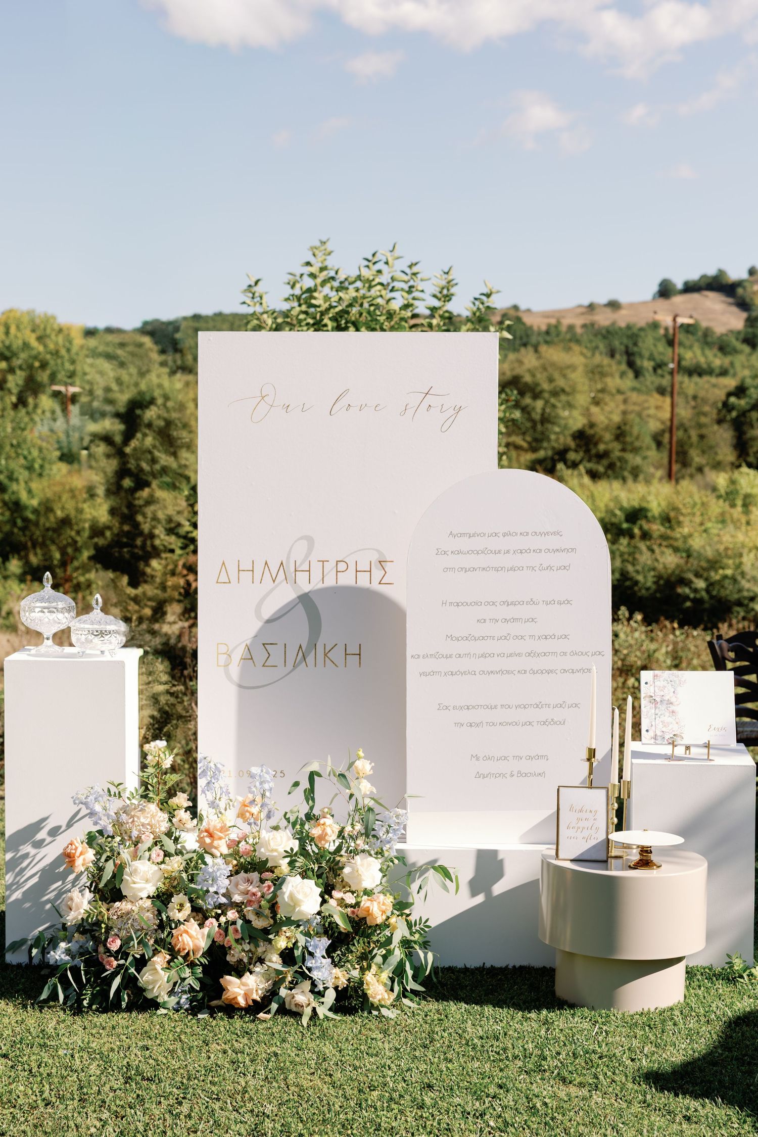 Elegant white wedding signage and floral arrangements displayed on green lawn.