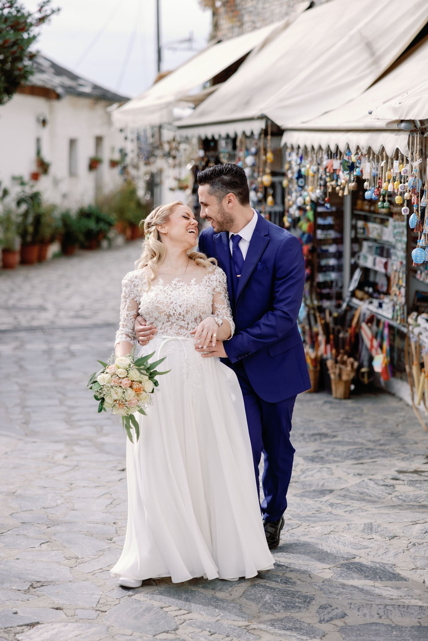 A romantic wedding photoshoot along a charming cobblestone street with market stalls.