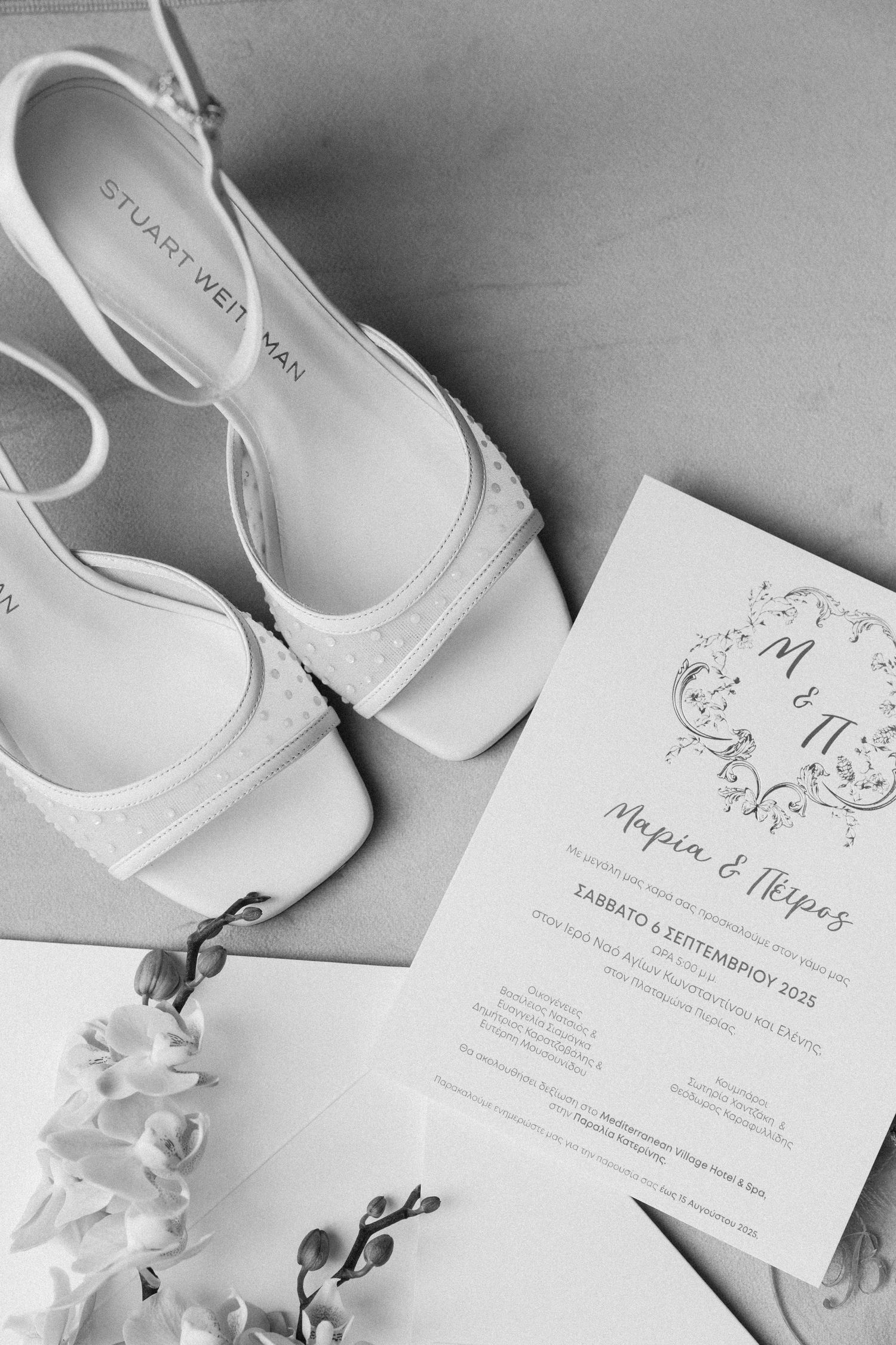 Elegant white wedding shoes and invitations arranged in a minimalist black and white composition.