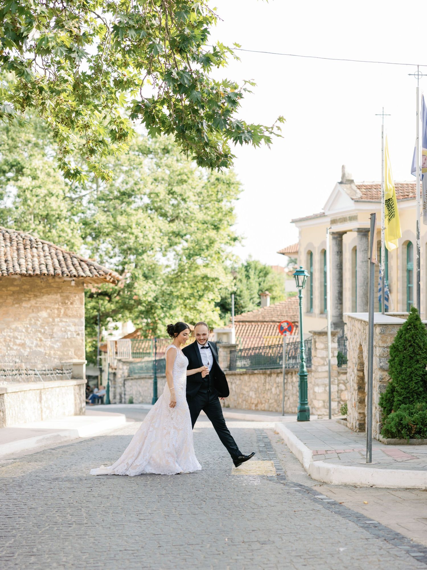 A romantic wedding portrait of a couple walking along a cobblestone street with stone buildings.