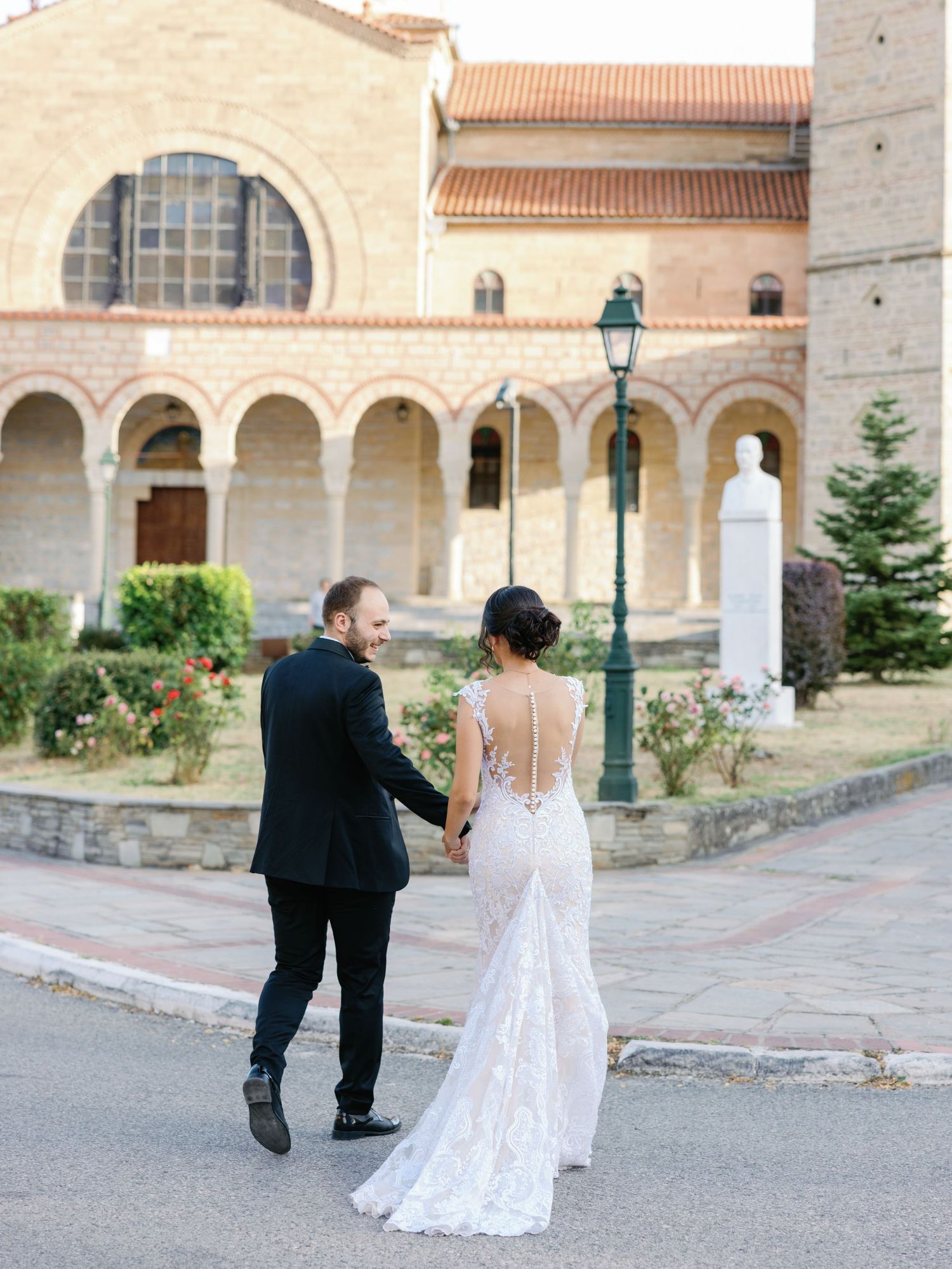 Wedding couple walking through courtyard of Mediterranean style stone building.