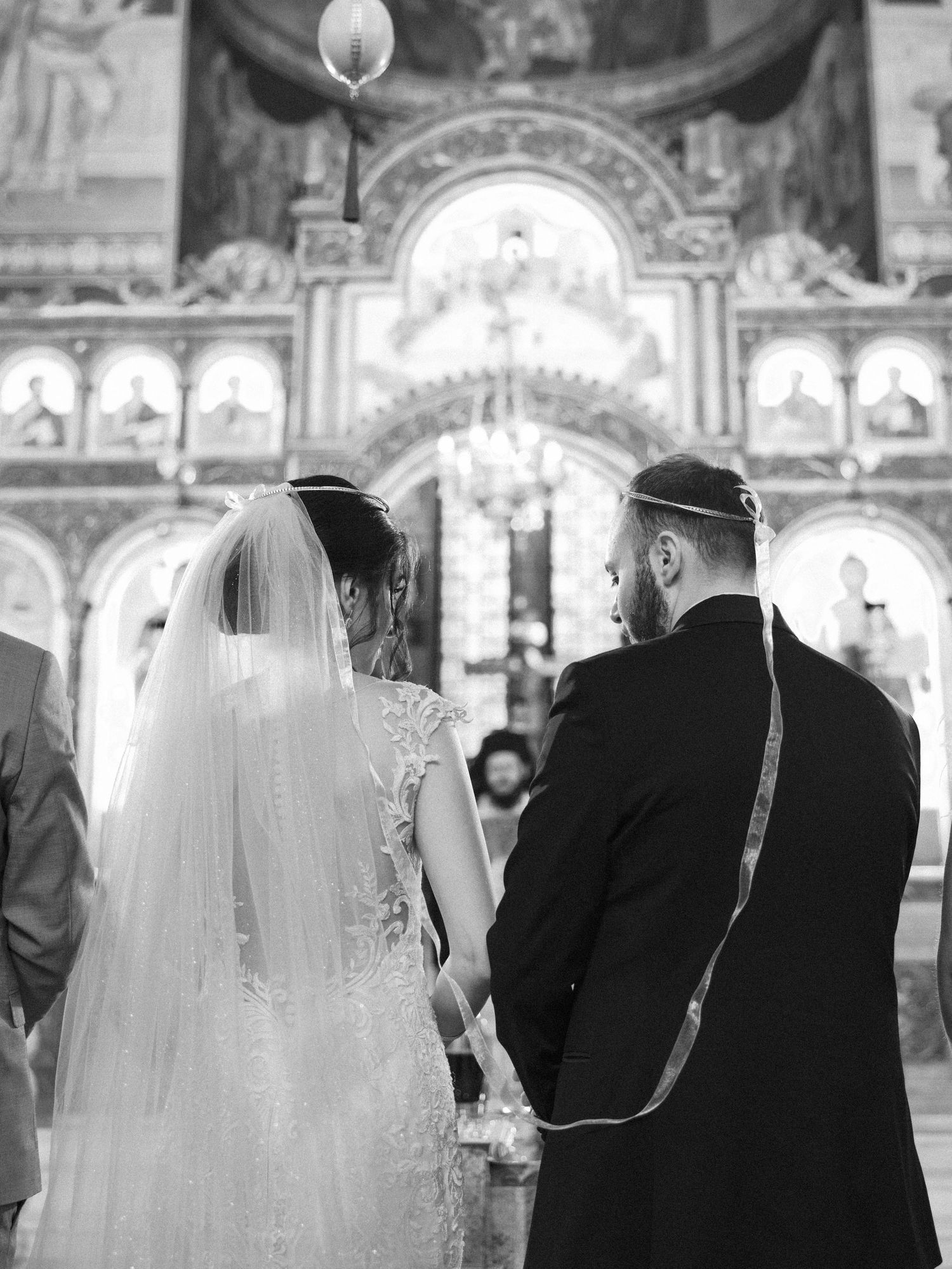 A black and white photo of a wedding ceremony in an ornate church with religious icons.