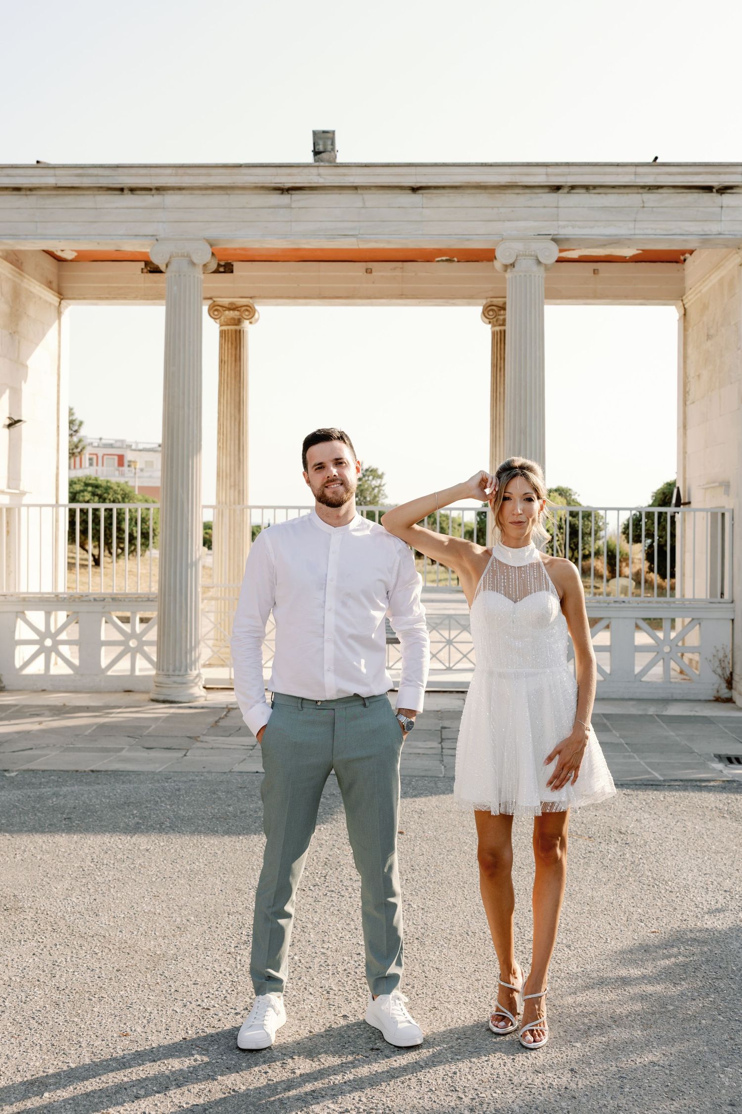 A casual engagement shoot featuring a couple in white and sage green outfits on a concrete terrace.