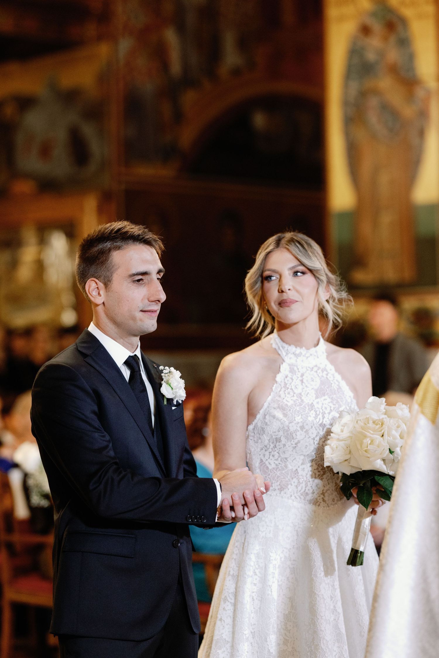 Wedding ceremony in an ornate church with beautiful chandeliers and decorative details.